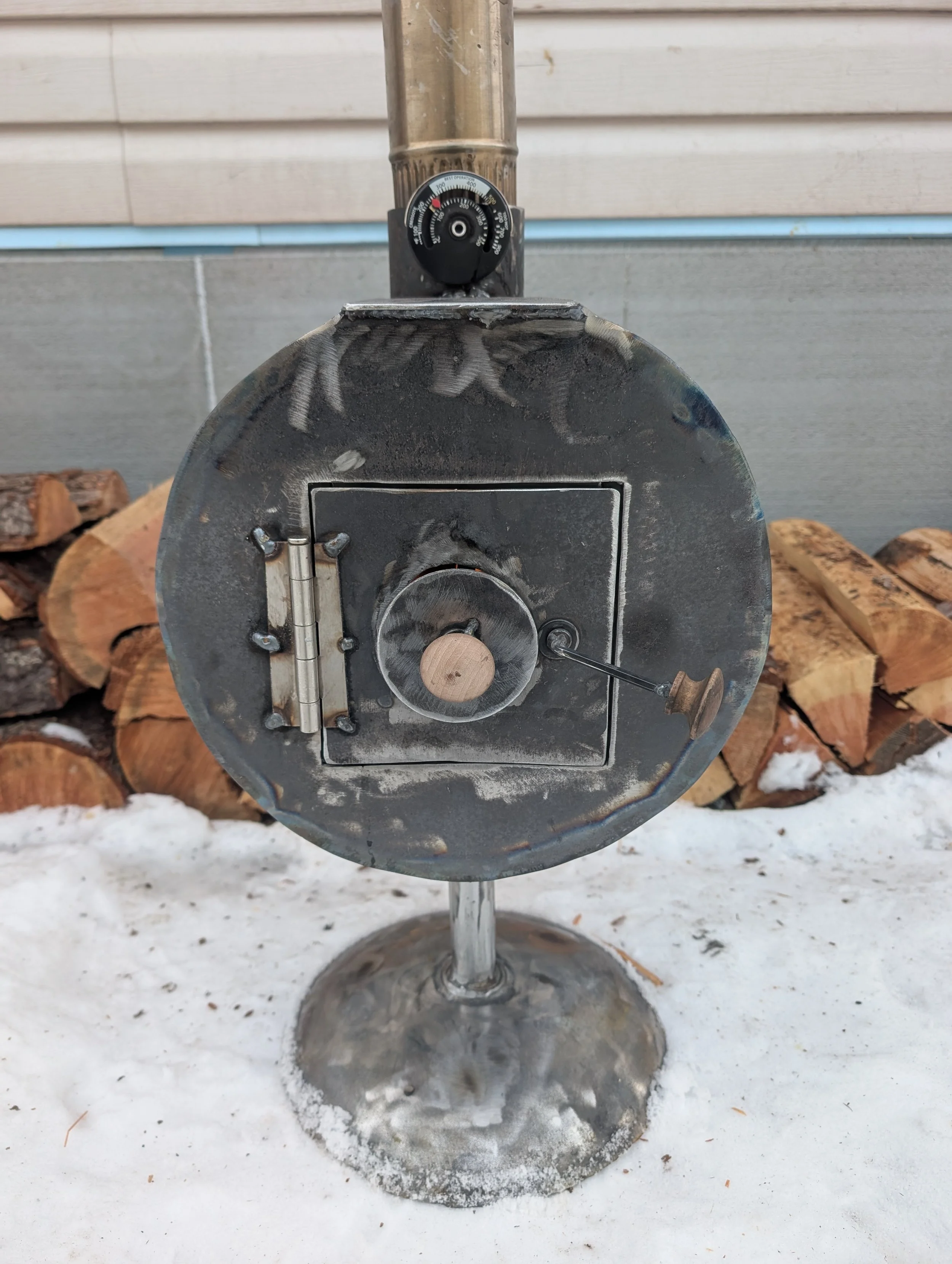 Close-up of a vintage metal ice cream or food slicer on a salt-covered outdoor surface, with stacked logs in the background.