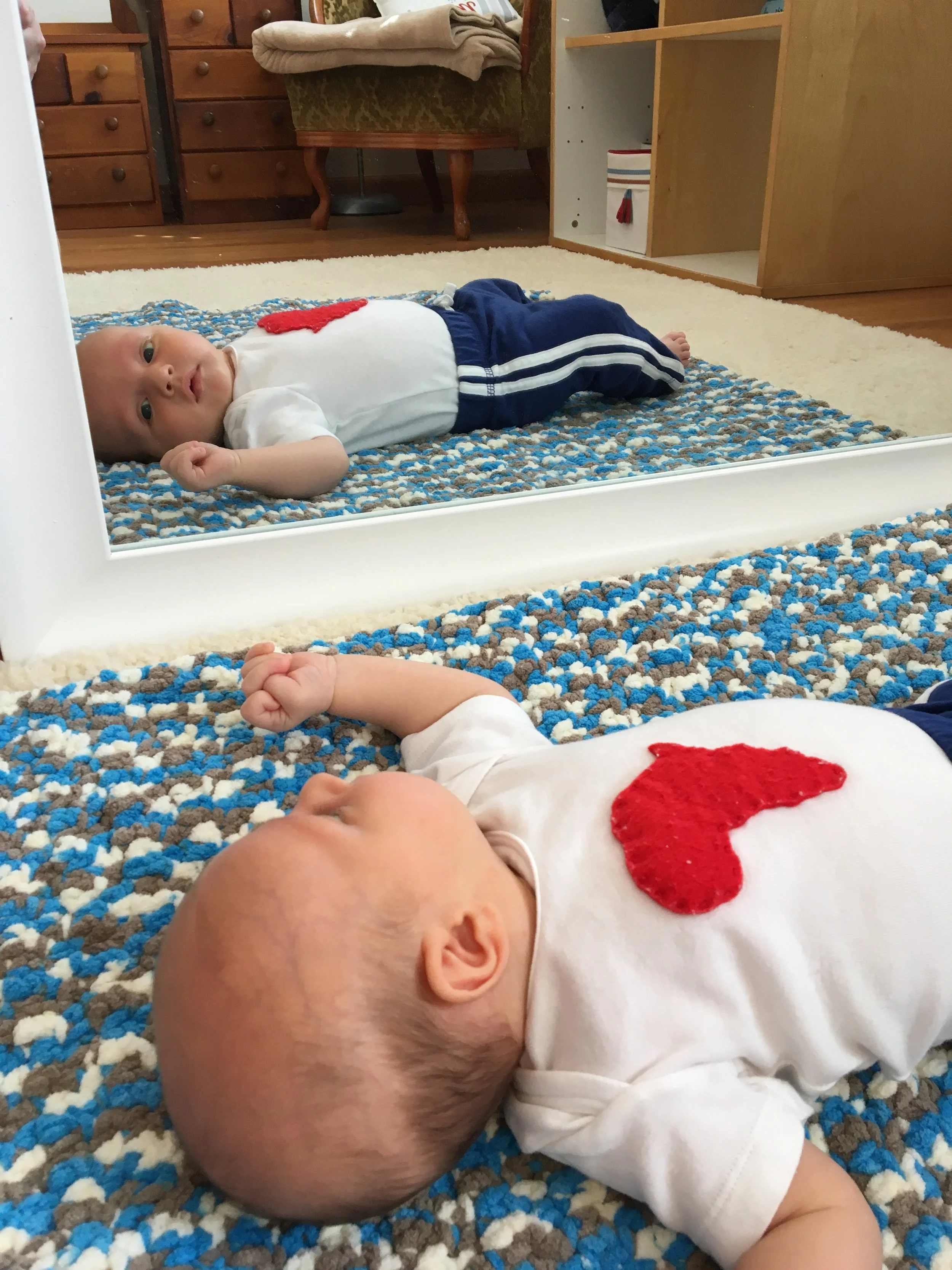 baby laying in front of mirror