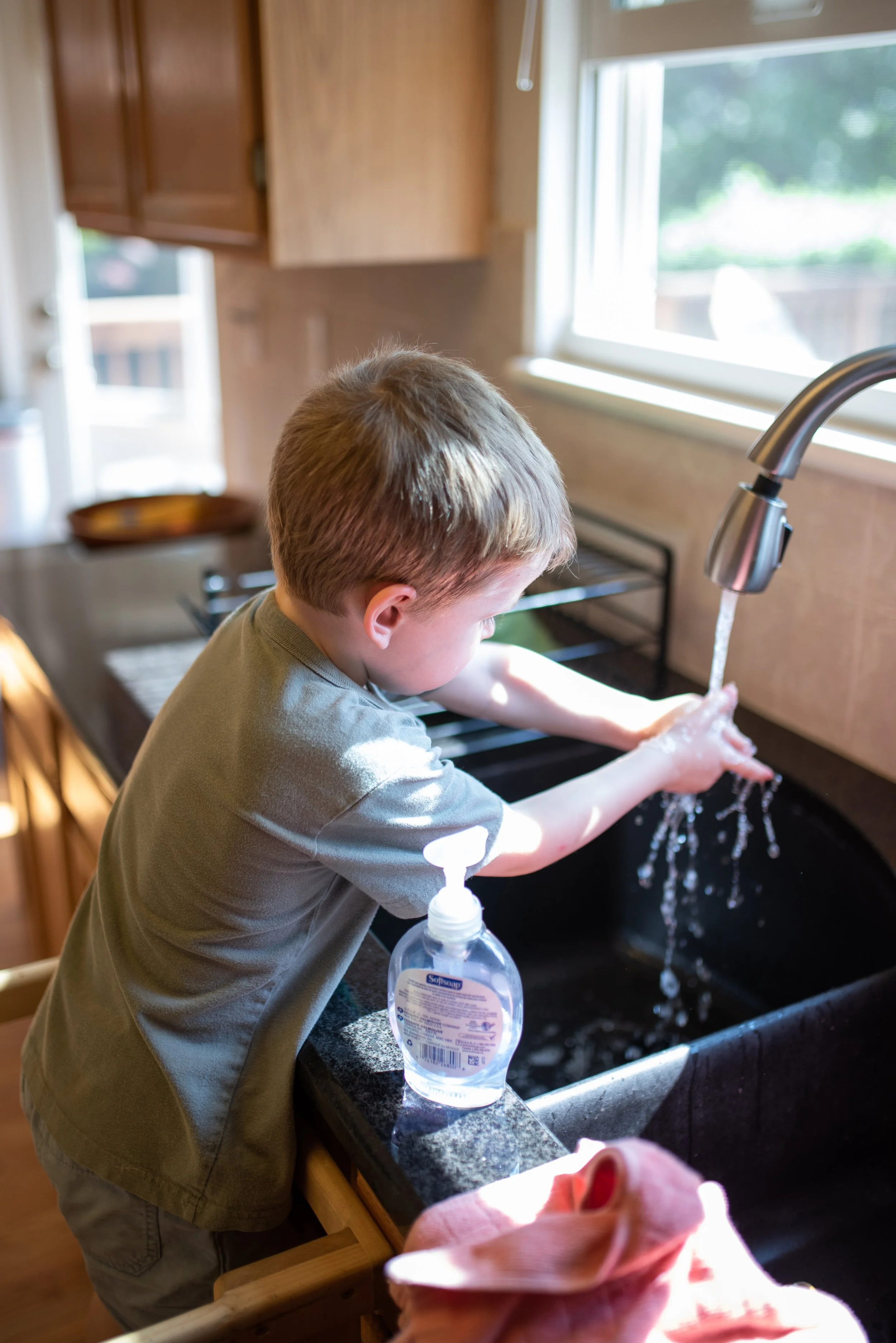 child washing hands in sink