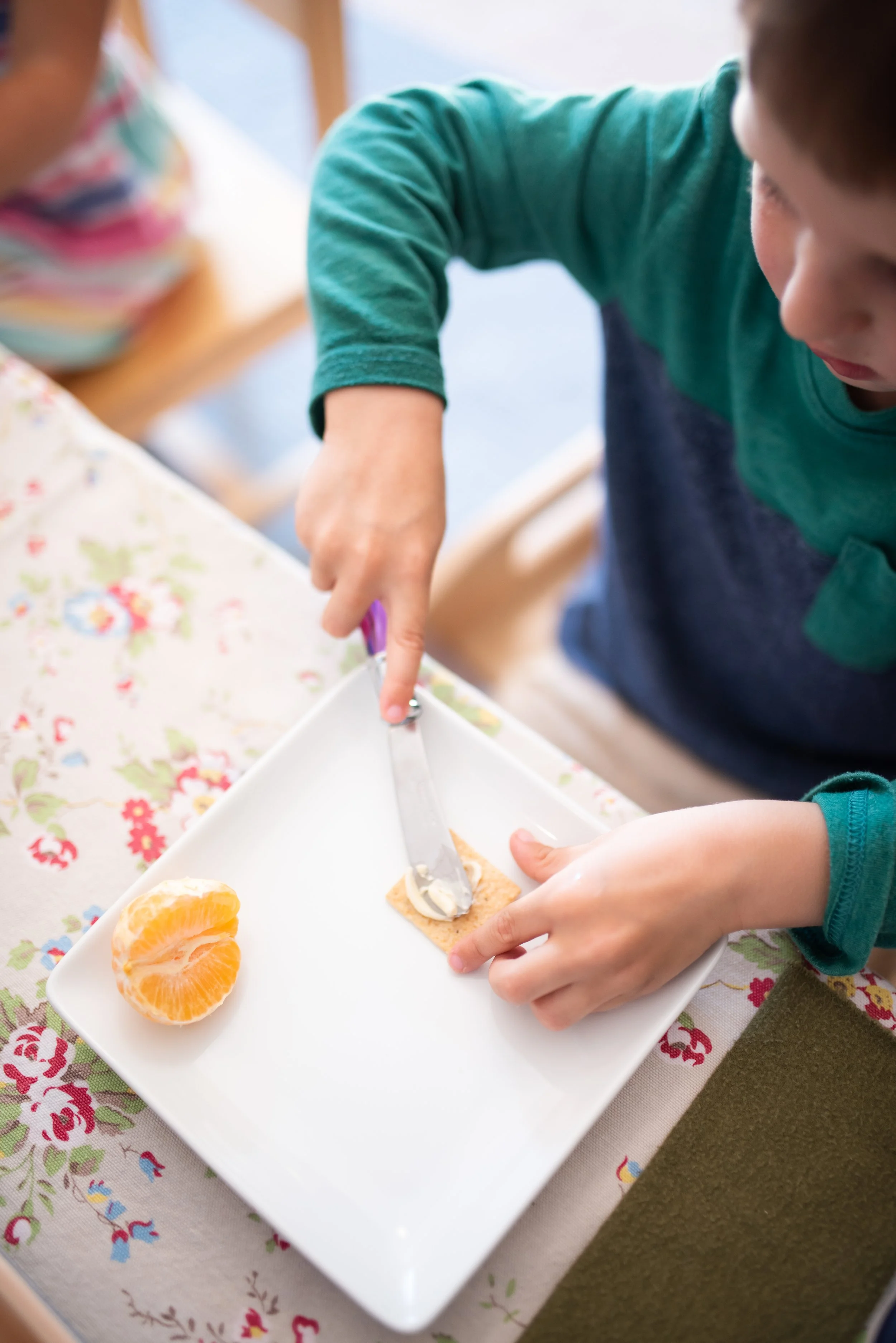 child buttering a cracker