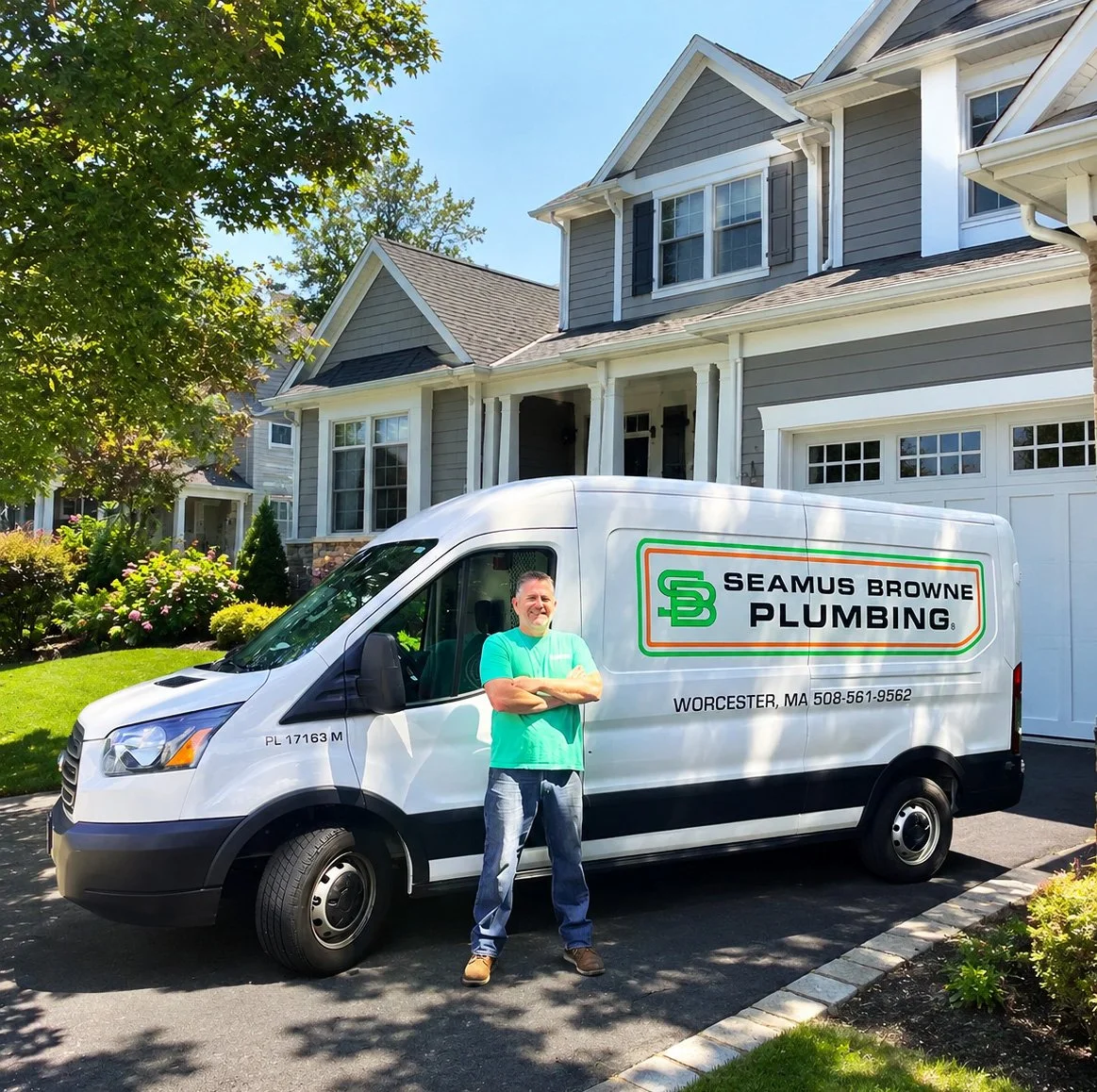 A man standing in front of a Seamus Browne Plumbing service van parked in a residential driveway. The house behind is a two-story home with gray siding, white trim, and a well-maintained lawn and garden.