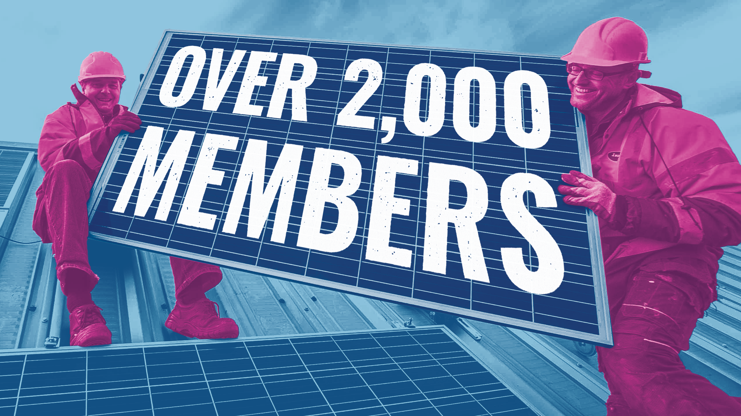 Two people wearing hard hats and workwear are holding up a alrge solar panel. On it, it reads 'Over 2,000 members'.
