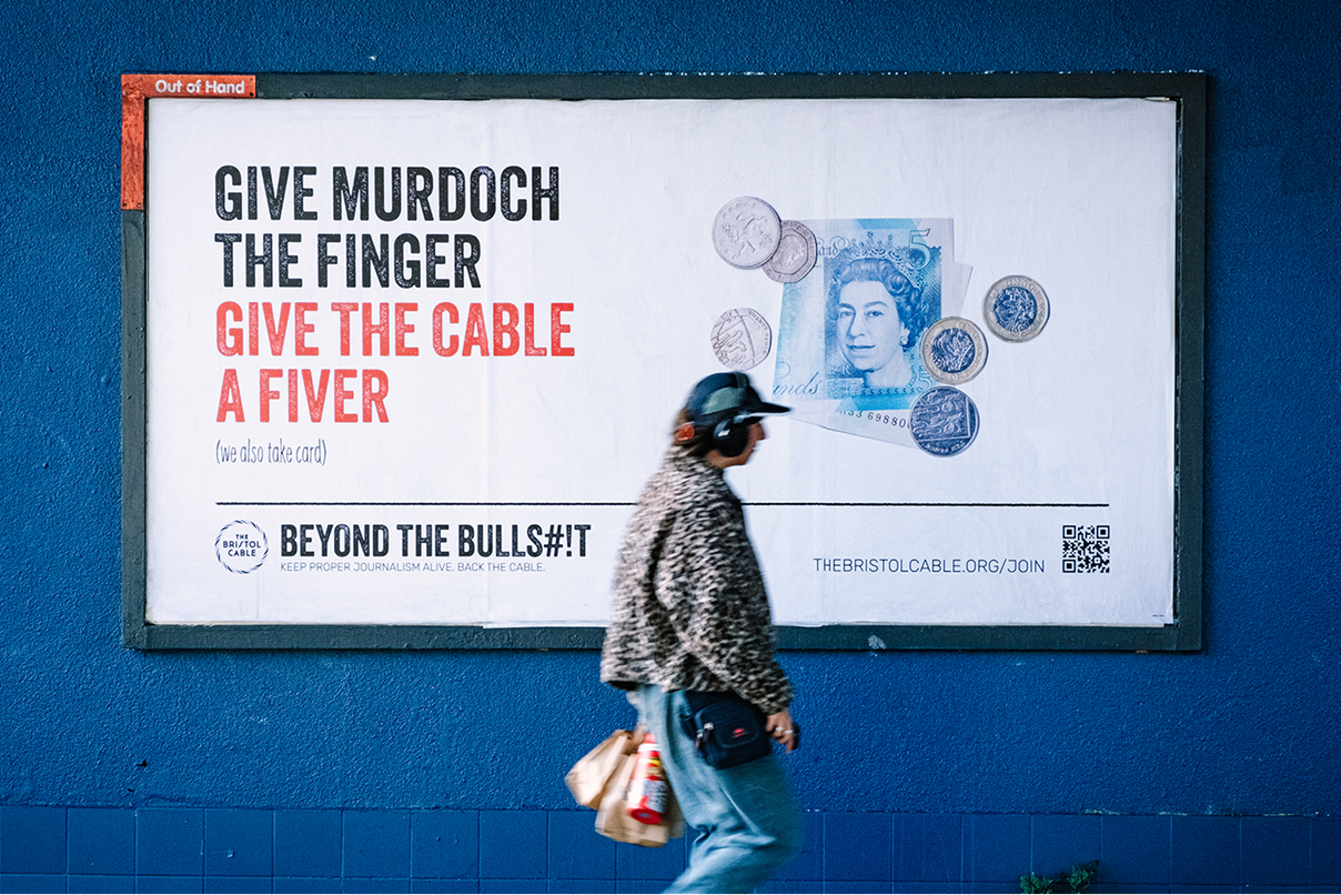 A person wearing headphones is walking infront of a billboard, which has an advert for the bristol cable on it. The wall behind it is bright prussian blue.