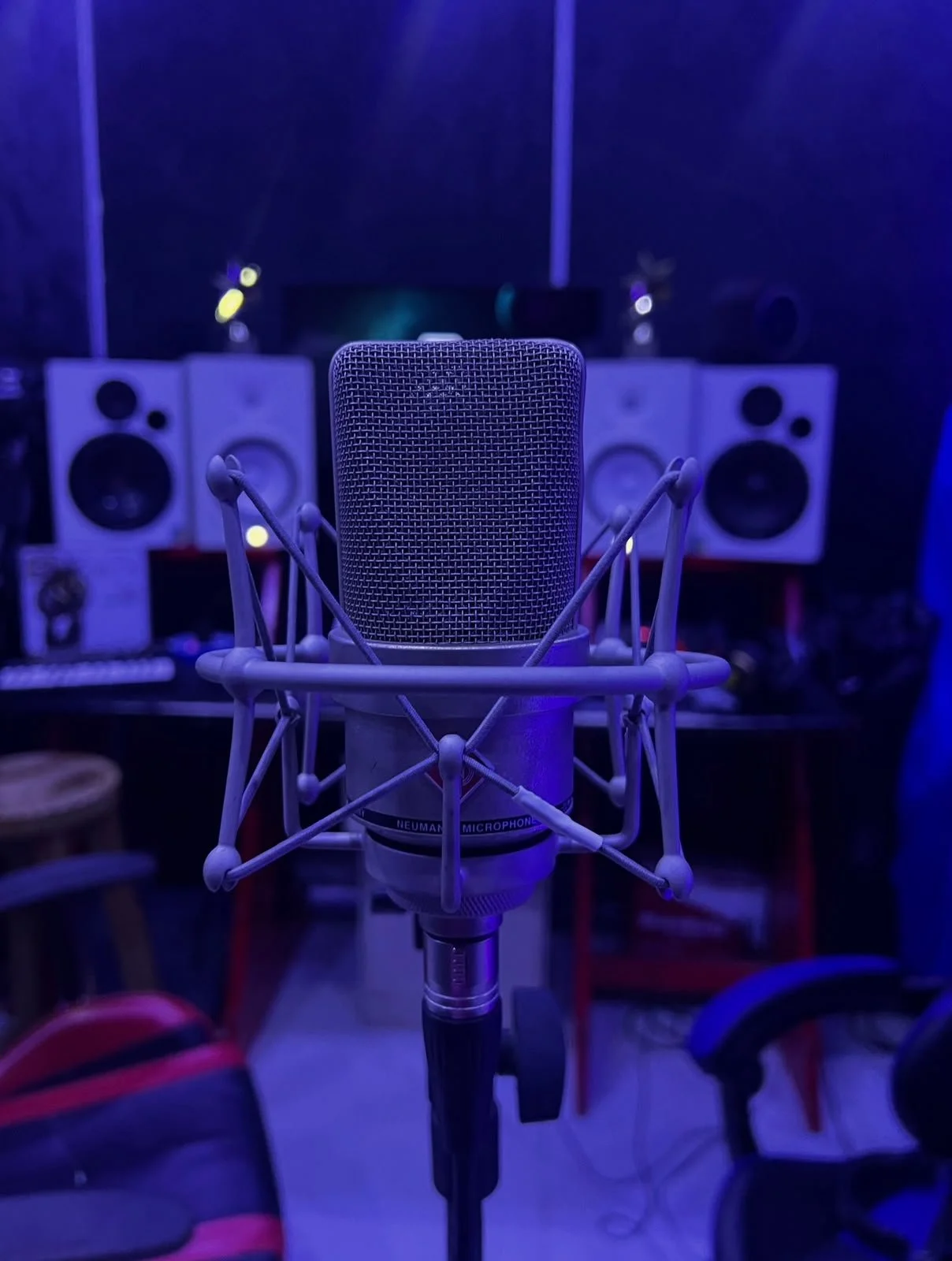 Micrófono de estudio delante de altavoces en un ambiente con iluminación azul.
