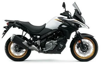 A white and black adventure motorcycle with gold accents, a large windshield, and rugged tires.