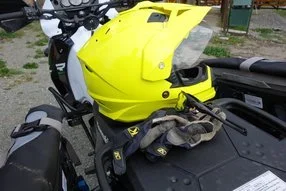 A bright yellow motorcycle with some tools and gloves resting on its seat, parked outdoors.