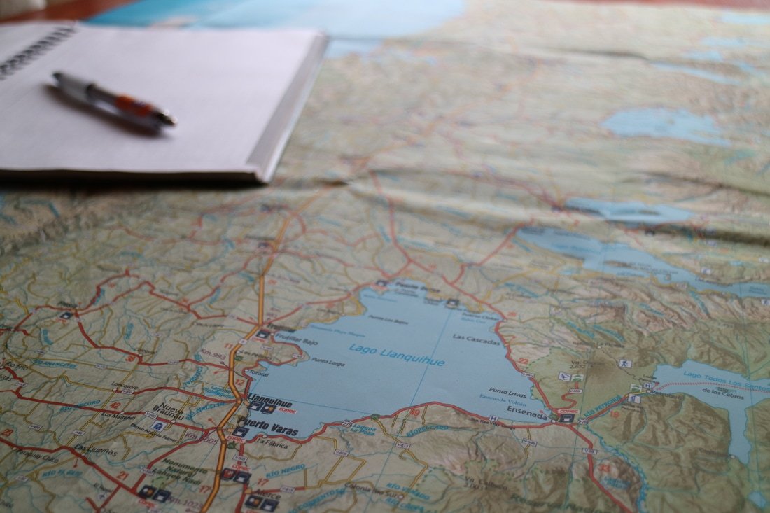 A map showing Lago Llanquihue, with roads, towns, and lakes in the surrounding area, along with a pen and a notebook placed on top.