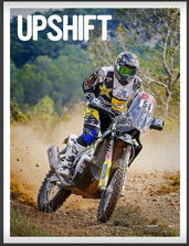 Motorcyclist riding off-road dirt trail, kicking up dust, in a wooded area