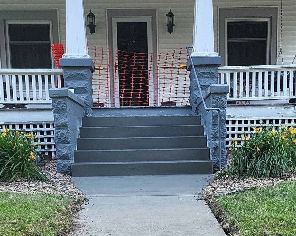Front porch with construction barrier and steps leading to a house.