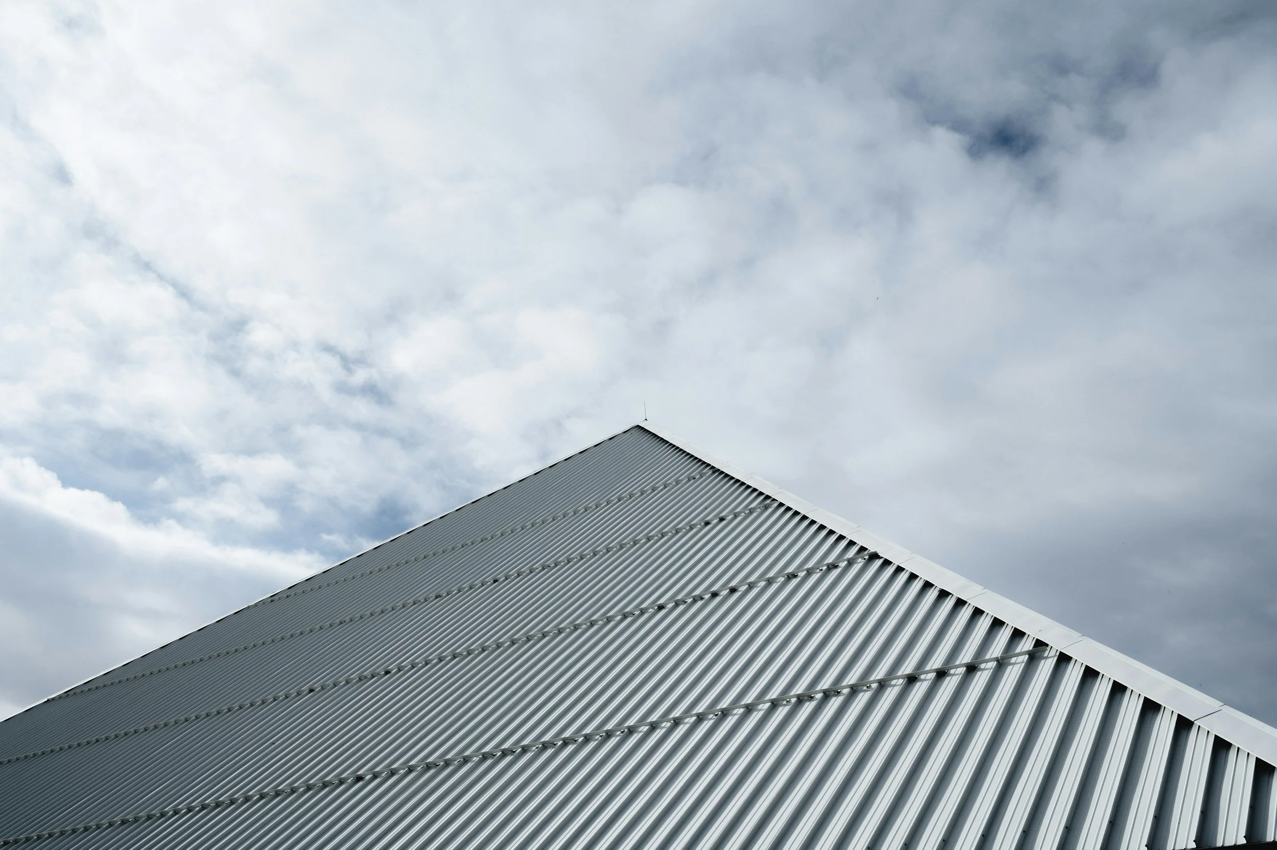 Close-up of a metal roof with a cloudy sky in the background.