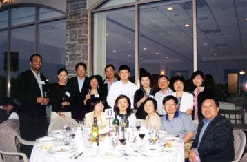 Group of people at a formal dinner in a restaurant with large windows and city view