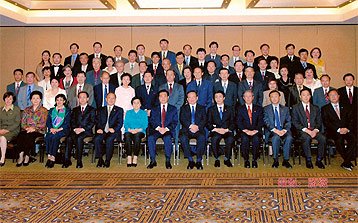 Group photo of many professionally dressed people in a conference room.