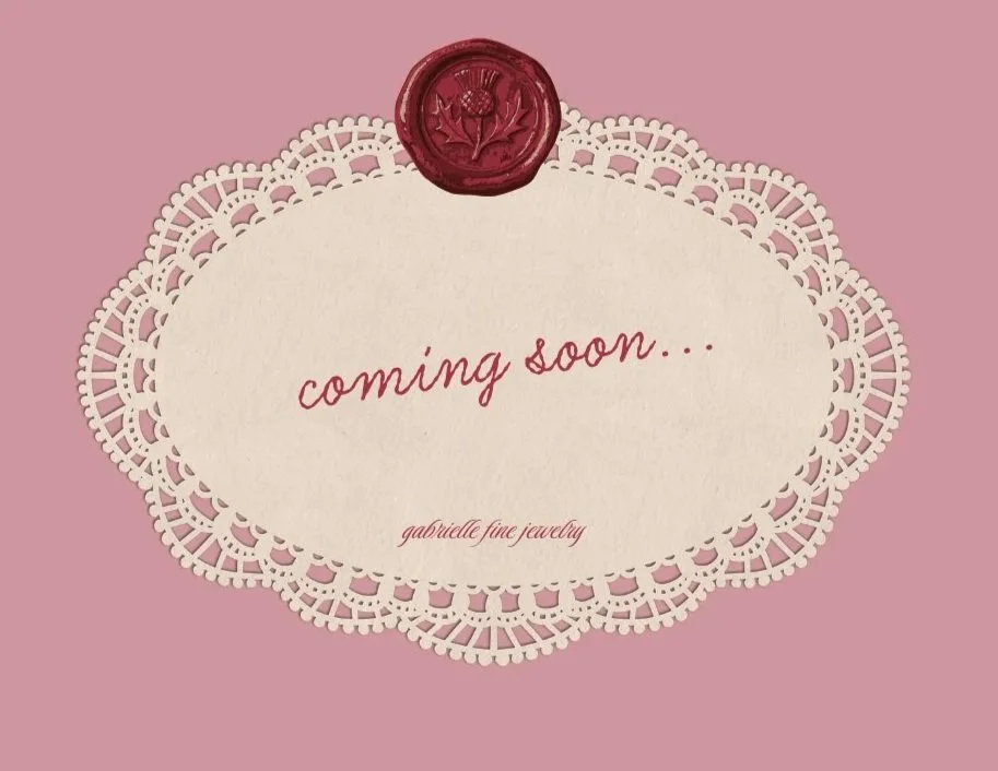 A pink background with an oval-shaped, white doily border. Inside, red cursive text reads 'coming soon...' and smaller text says 'gabrielle fine jewelry.' A red wax seal with a floral design is at the top of the doily.