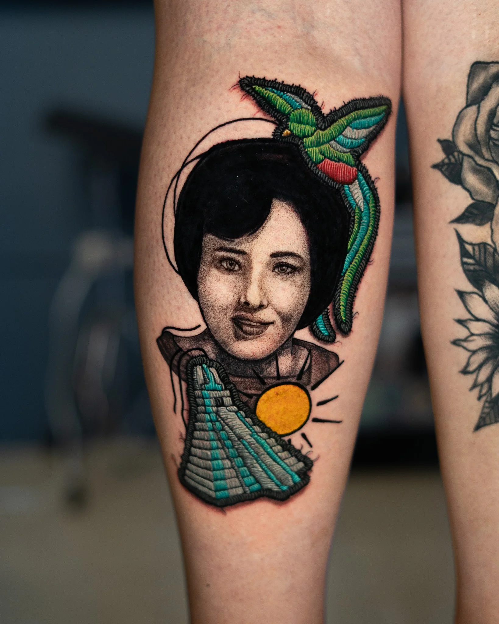 Tatuaje de una mujer con cara en estilo retrato en blanco y negro, con un quetzal colorido y la ruina de tikal en estilo parche,  tatuaje con efecto de hilos. Tatuaje hecho por Benjamin Saenz en Antigua Guatemala, en el tattoo shop: Sublime Tattoo