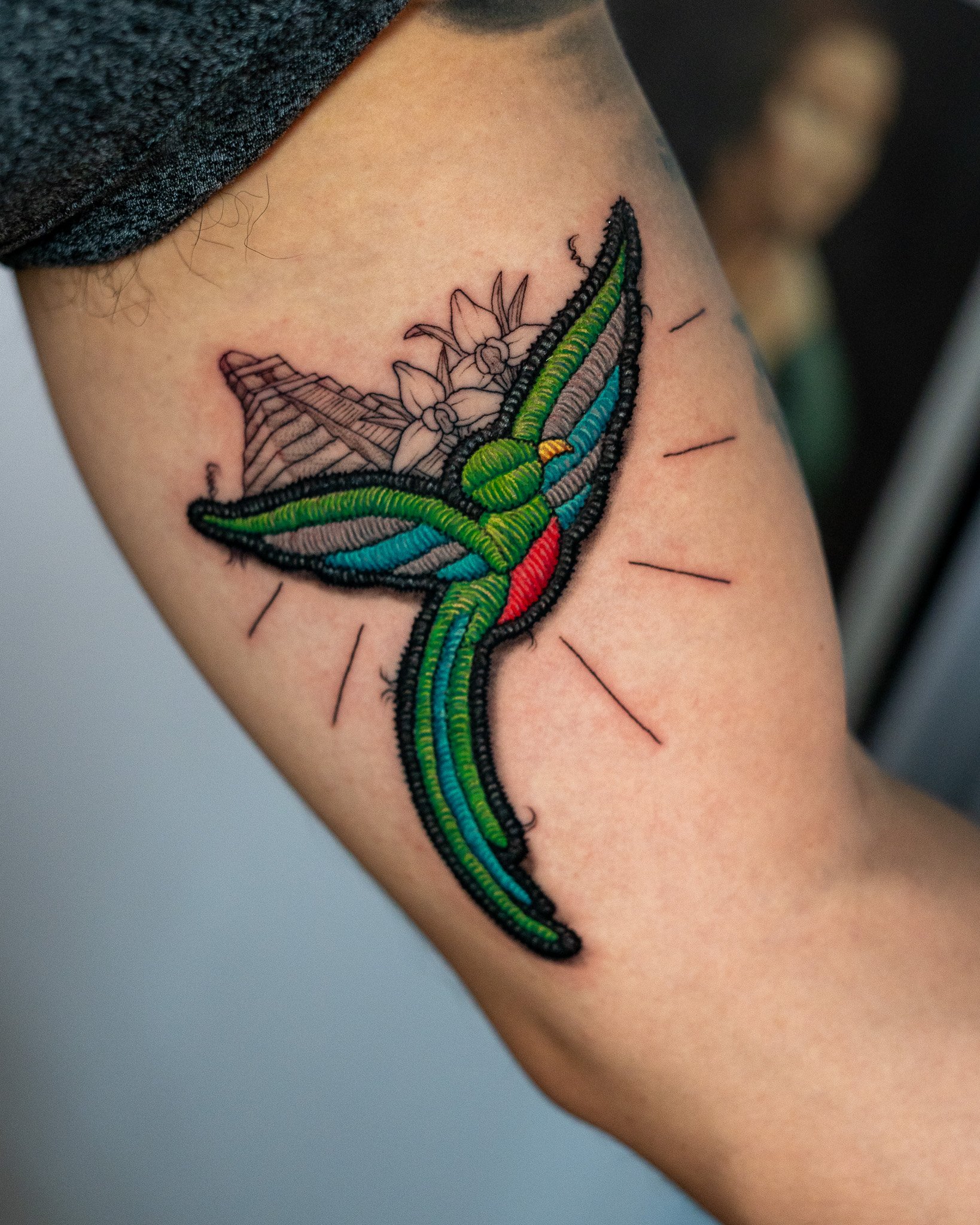 Tatuaje de un quetzal en el brazo con un diseño bordado. tatuaje estilo parche hecho en Antigua Guatemala, Guatemala. Tatuaje tejido, tatuaje con efecto de hilos. Tatuaje hecho por Benjamin Saenz en Antigua Guatemala, en el tattoo shop: Sublime 