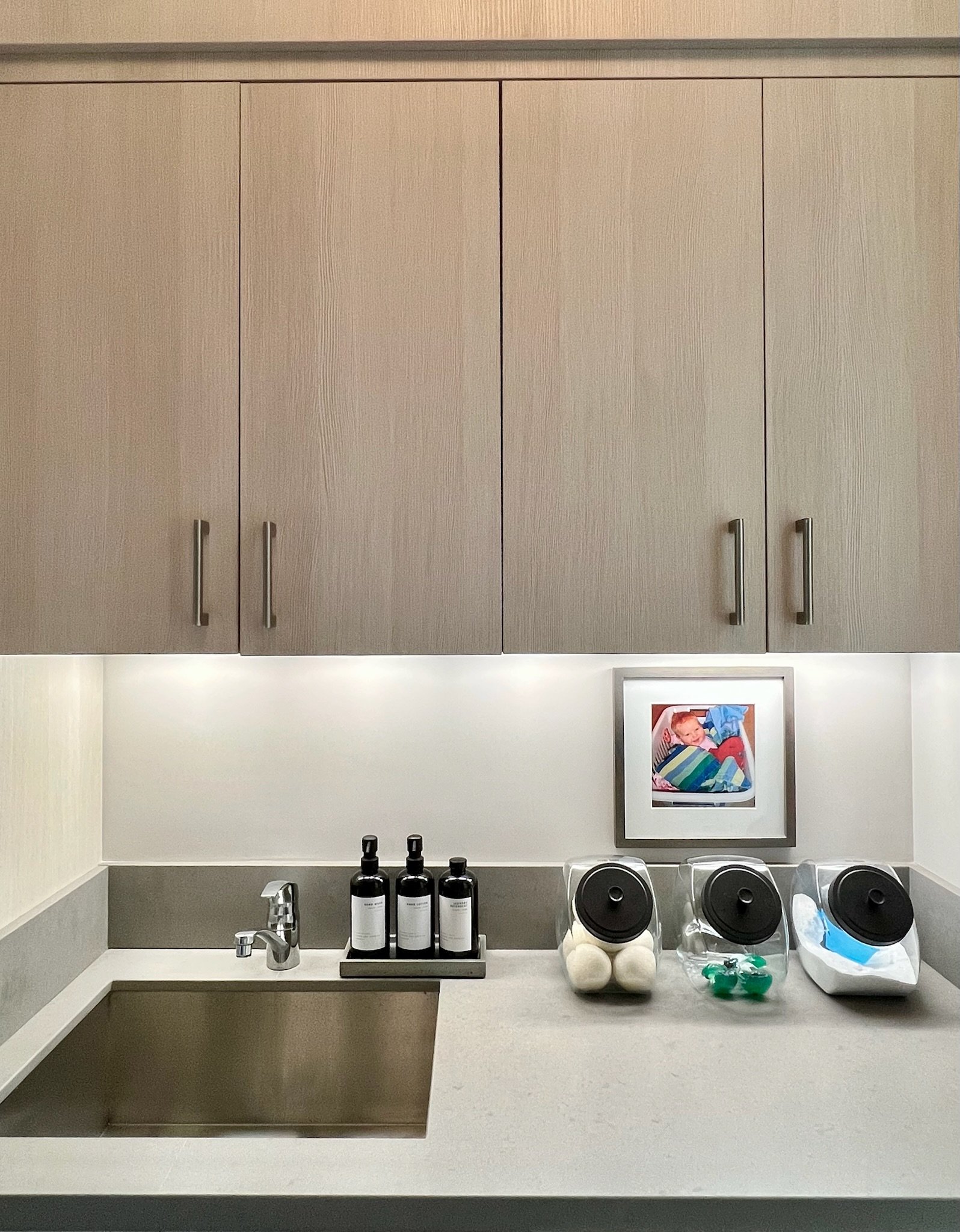 Organized laundry room with custom cabinetry and counter