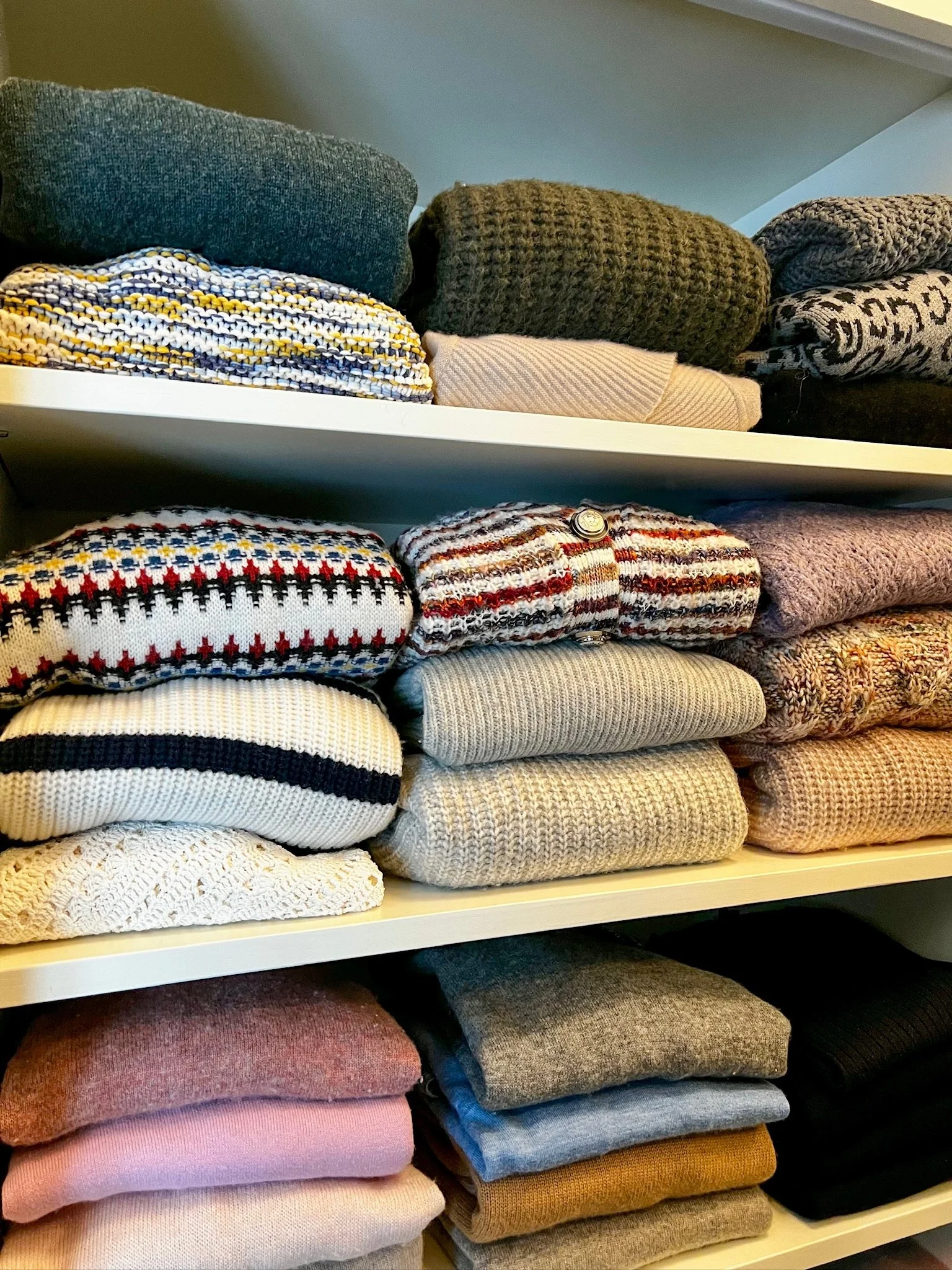 Professionally folded sweaters on a custom closet shelf