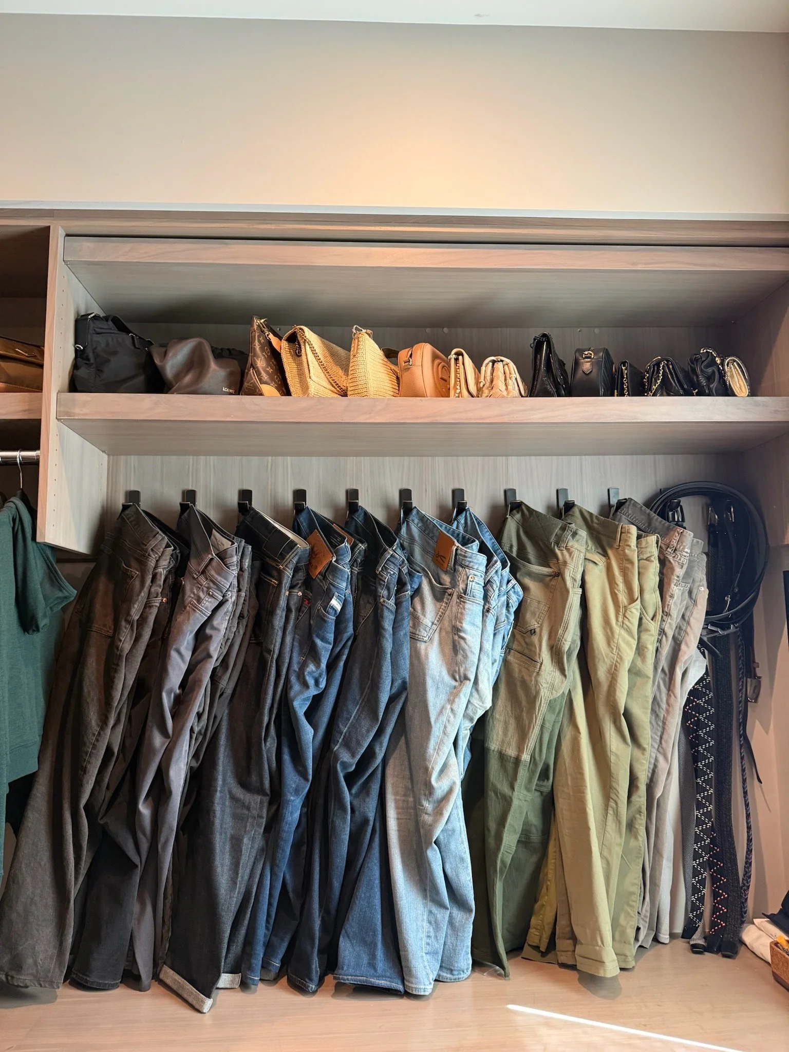 Organized closet with folded denim and leather handbags