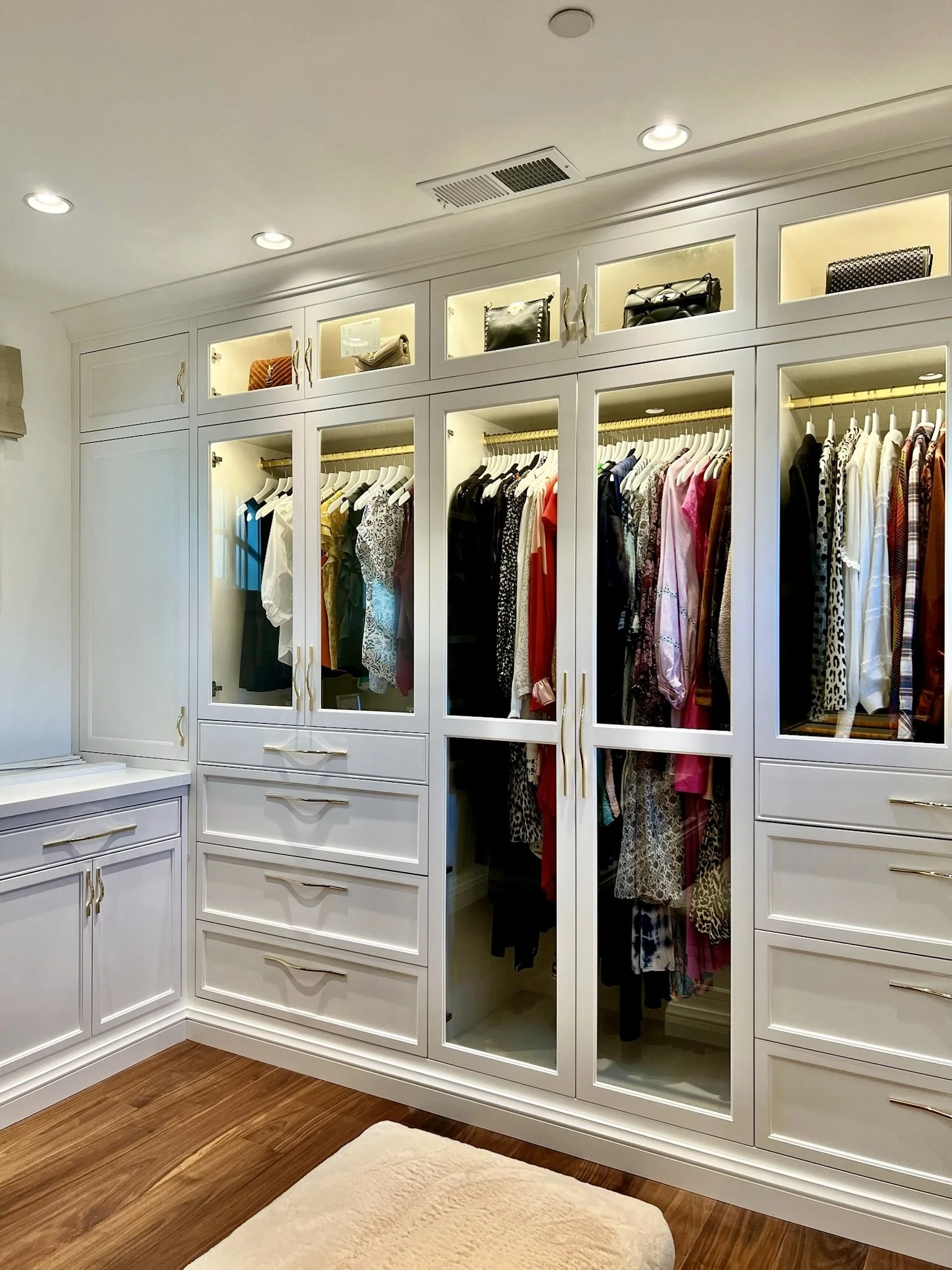 Luxury organization in a mirrored walk-in closet with custom cabinetry