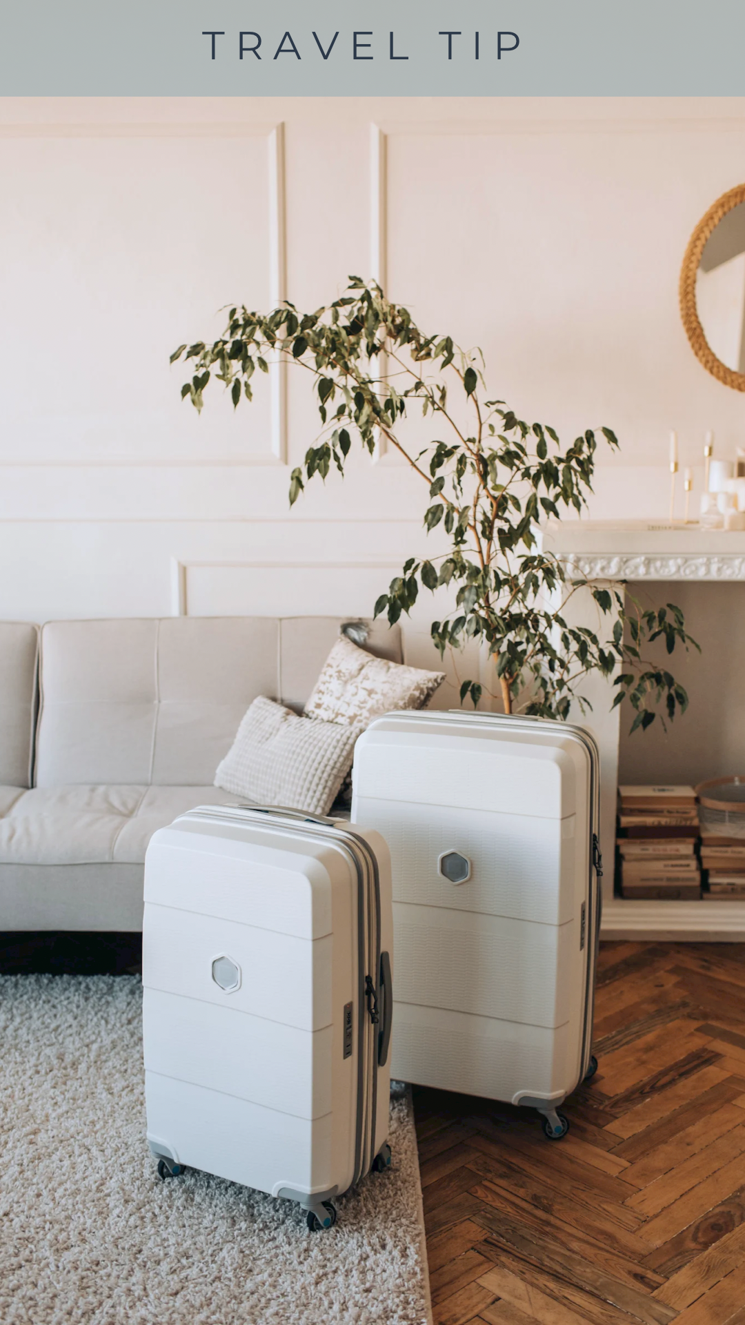 Interior of a living room with a beige sofa, patterned pillows, a large potted plant, two white suitcases, a white fireplace, and a round mirror on the wall under a gray panel with the text 'Travel Tip'.