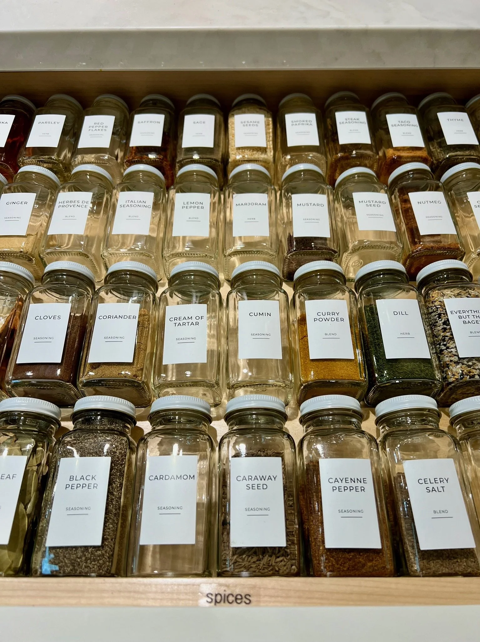 Organized spice drawer with labeled glass jars