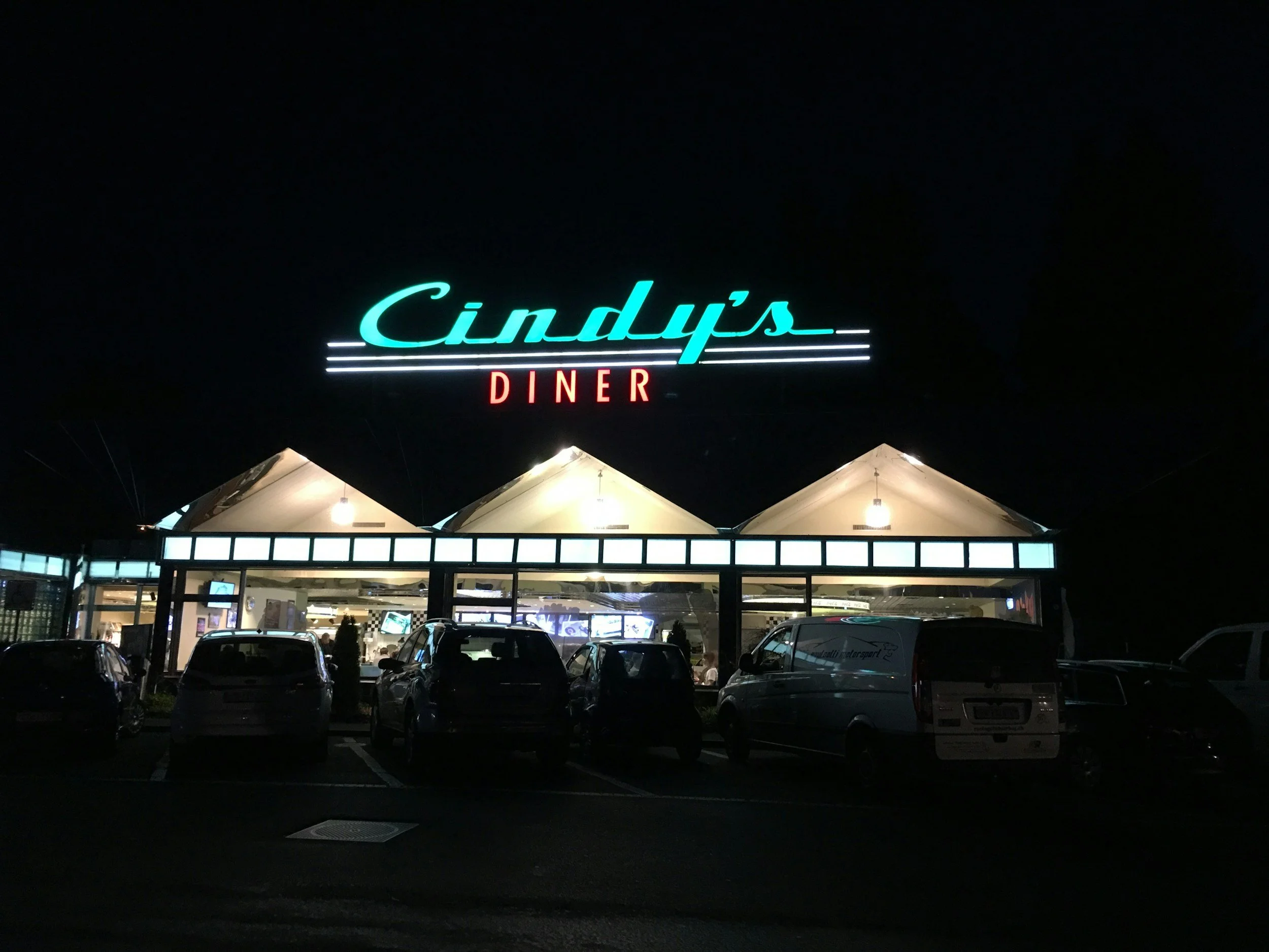 A brightly lit retro diner at night beneath a neon sign.
