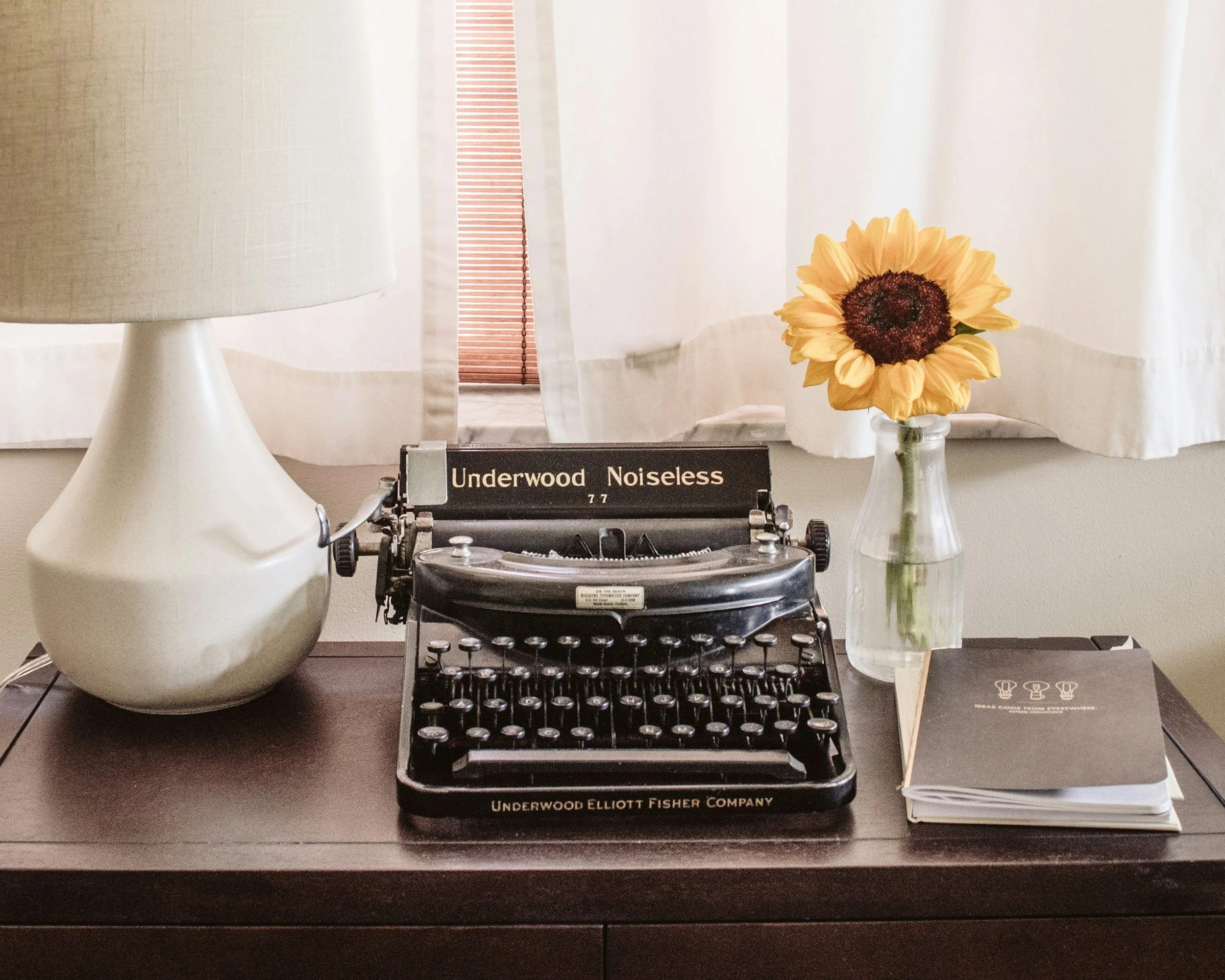 Vintage typewriter and sunflower on a warm writing desk.