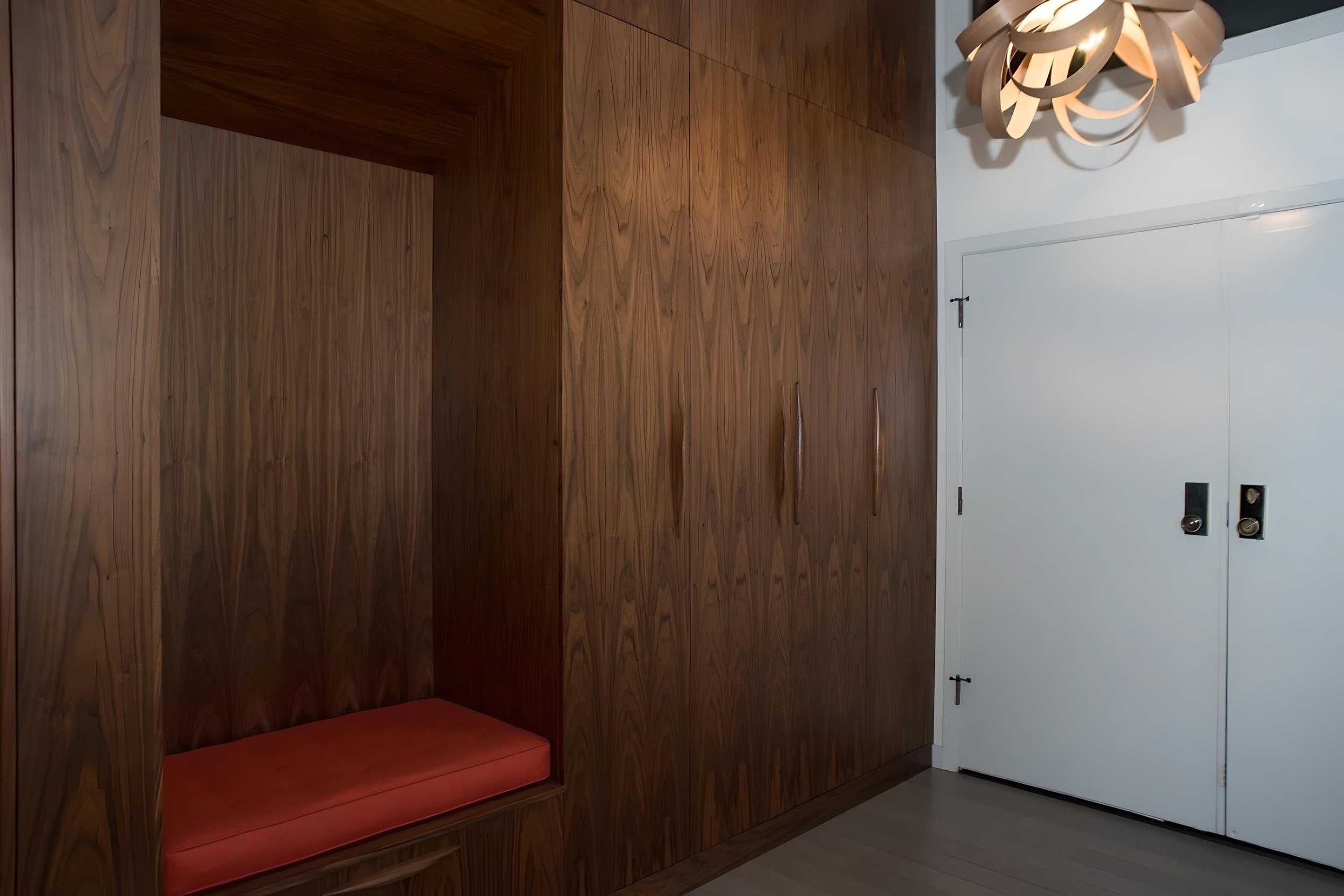 Interior of a room with wooden built-in cabinets, a white door, and a modern ceiling light fixture.
