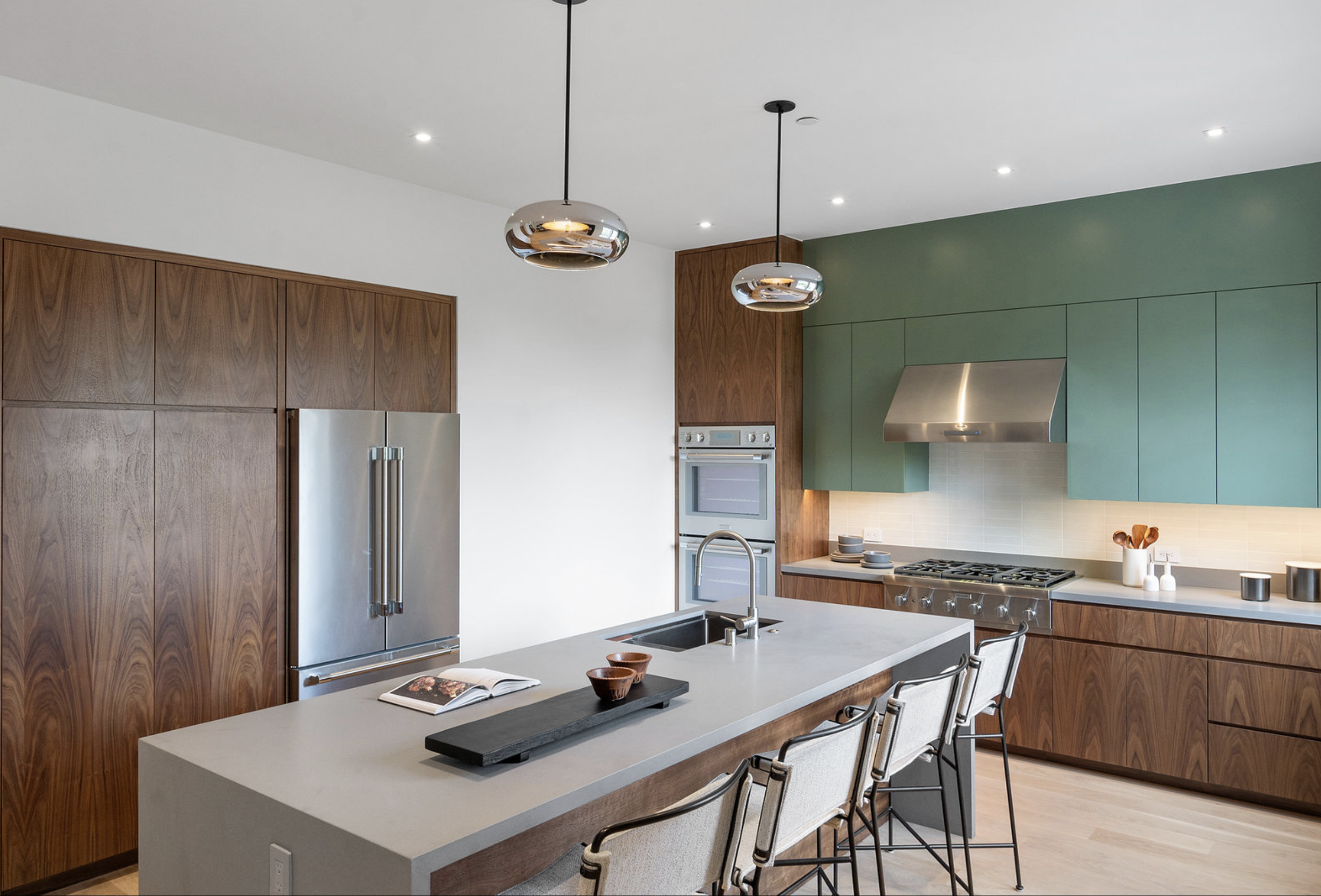 Modern kitchen with wooden cabinets, stainless steel appliances, and a green accent wall.