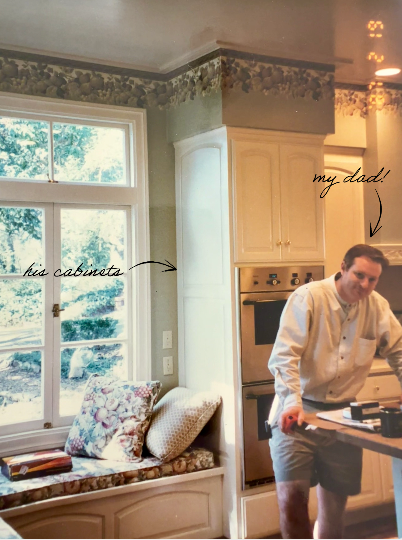 A man in a white shirt and shorts standing in a kitchen near a window and cabinets, with handwritten annotations 'his cabinets' pointing to the cabinets and 'my dad!' pointing to the man.