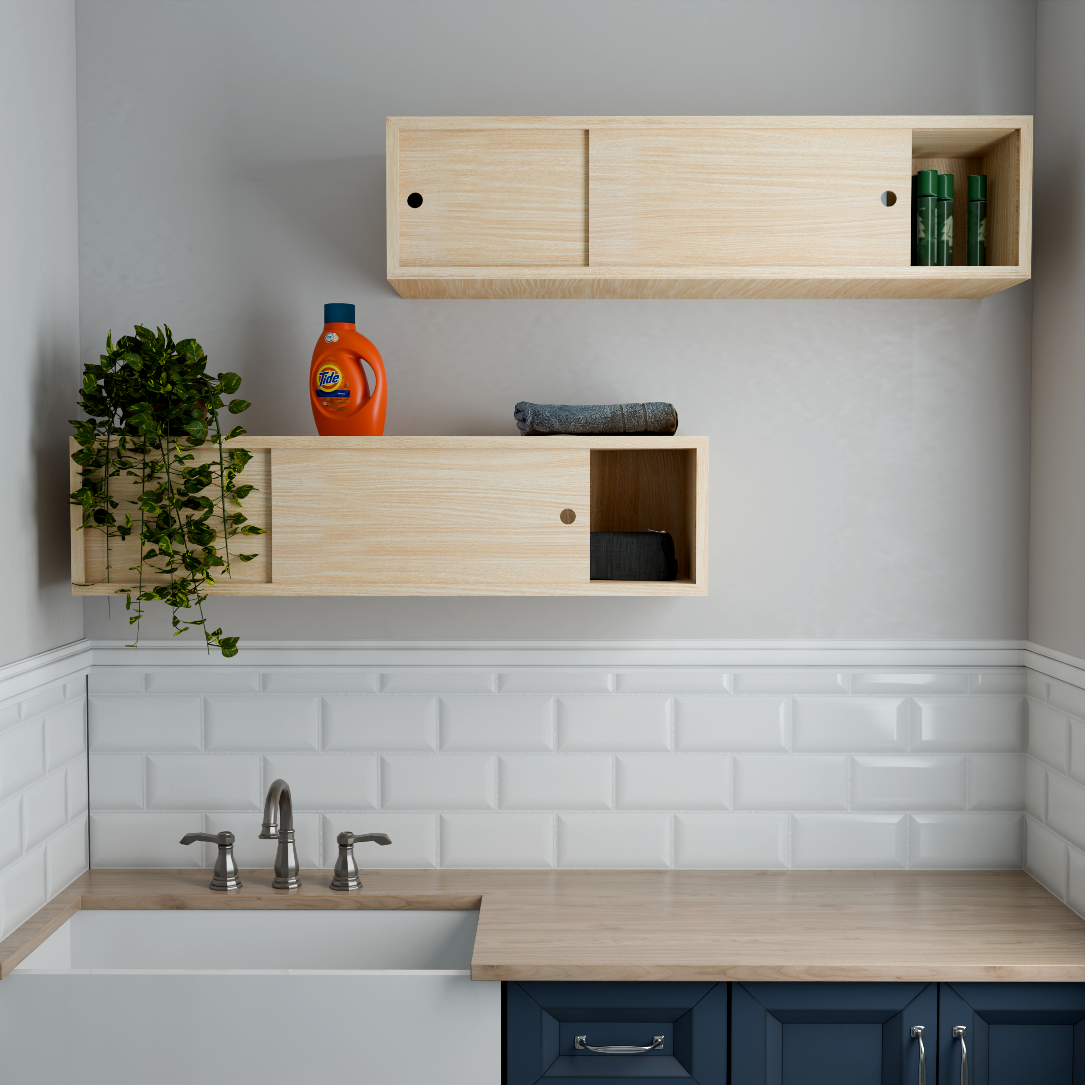 Top-down view of a modern kitchen with a light natural wood upper cabinet, a small green potted plant on the kitchen counter, a bottle of Tide laundry detergent, a folded gray towel, a blue lower cabinet with a silver handle, and a white tiled backsp