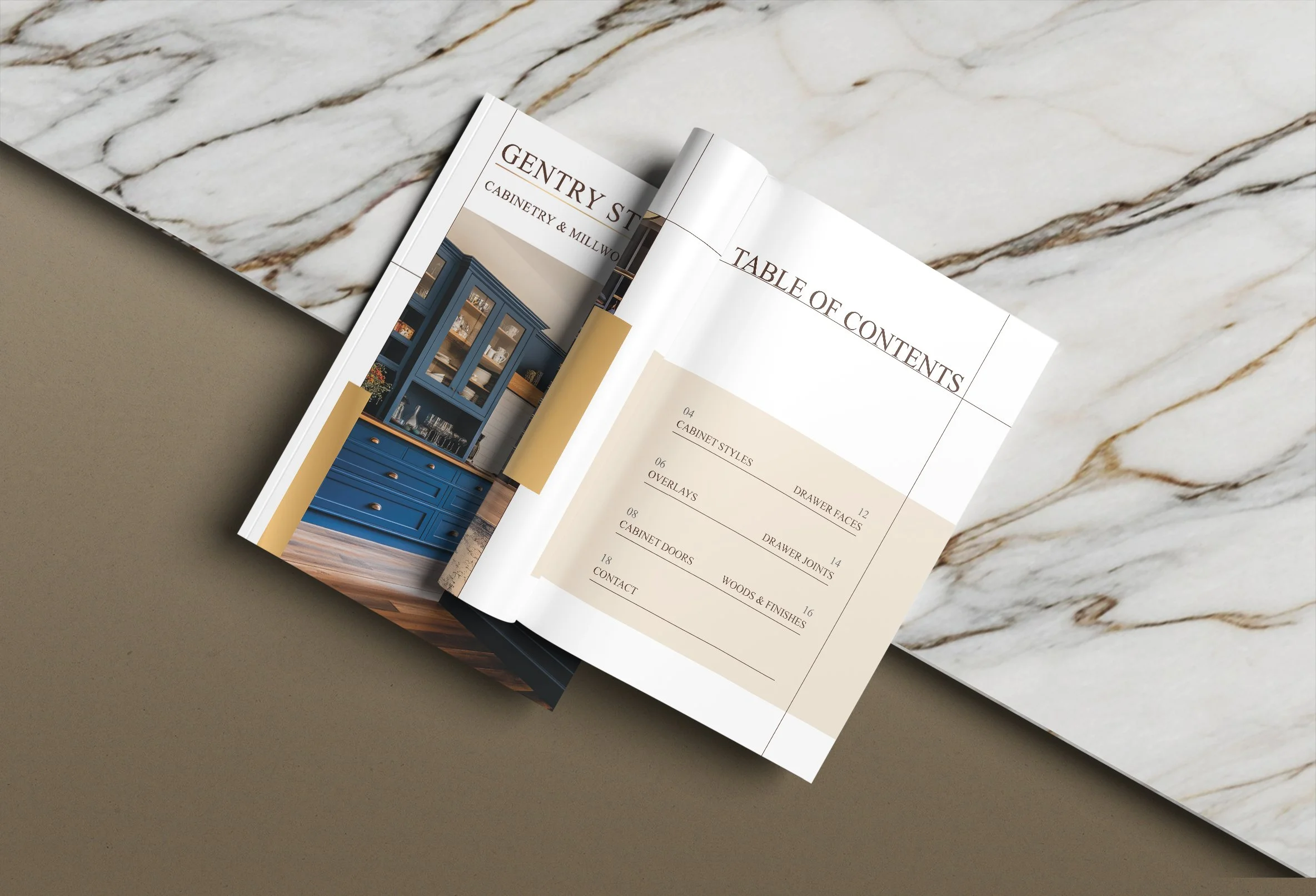 Open magazine showing a table of contents page with kitchen furniture images, on a marble surface.