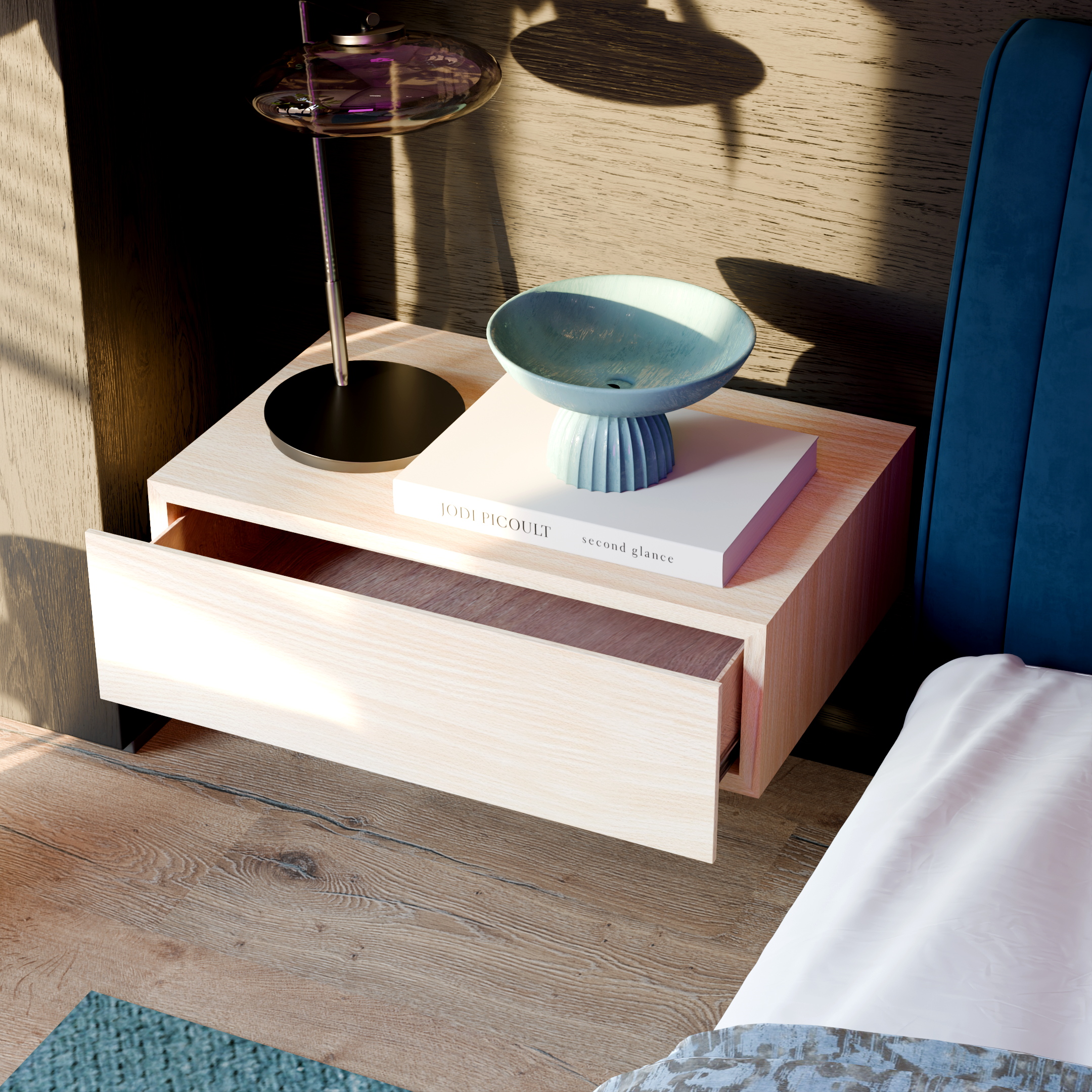 Close-up of a light wooden table displaying a blue ceramic bowl, a black lamp, and a transparent purple glass vase on top of a book titled 'second glance' by Jodi Picoult, with a textured wooden wall background.