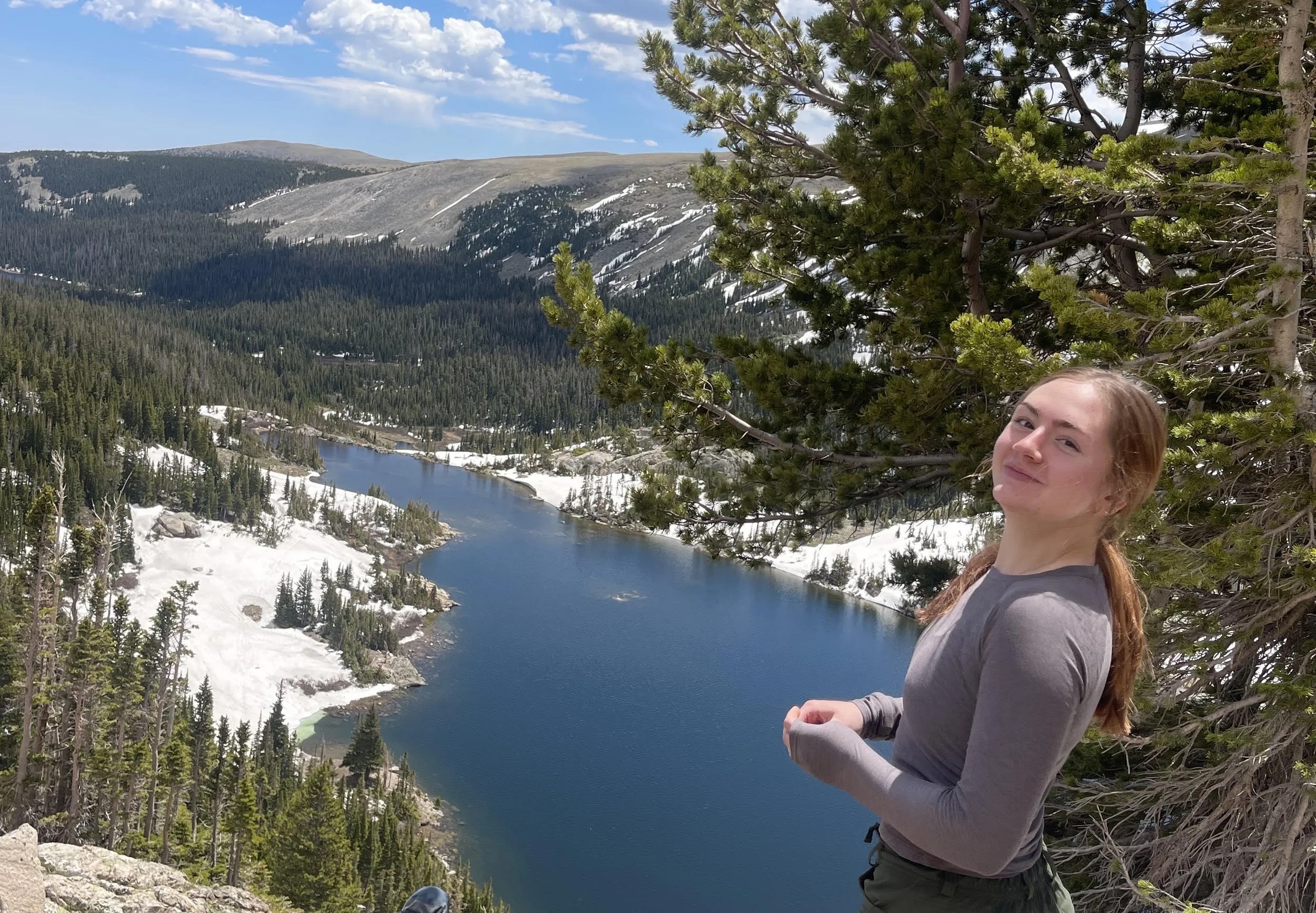 Abigail standing in front of an alpine lake