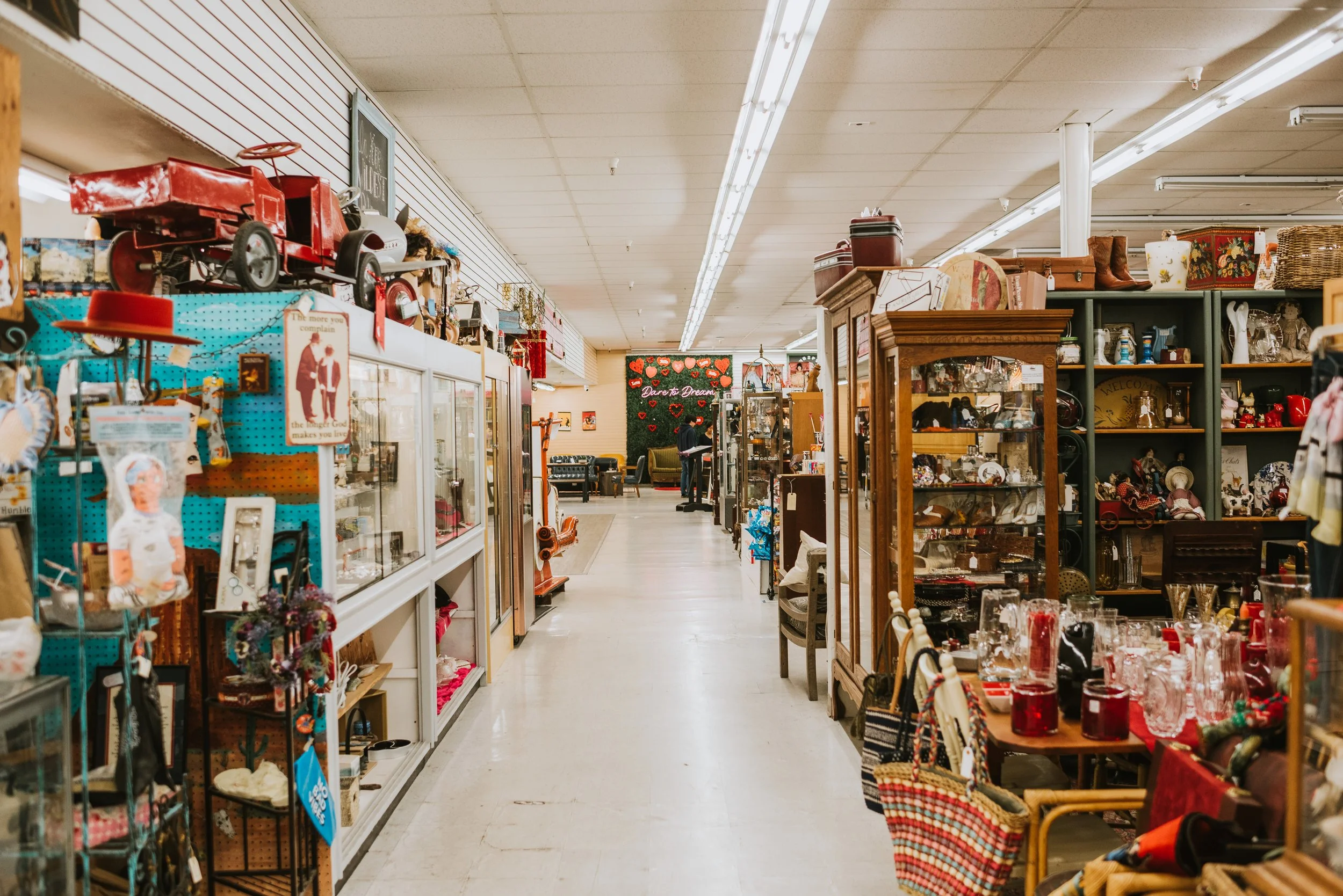 Aisle in an antique store filled with various vintage items, decorations, and collectibles on shelves and display cases.