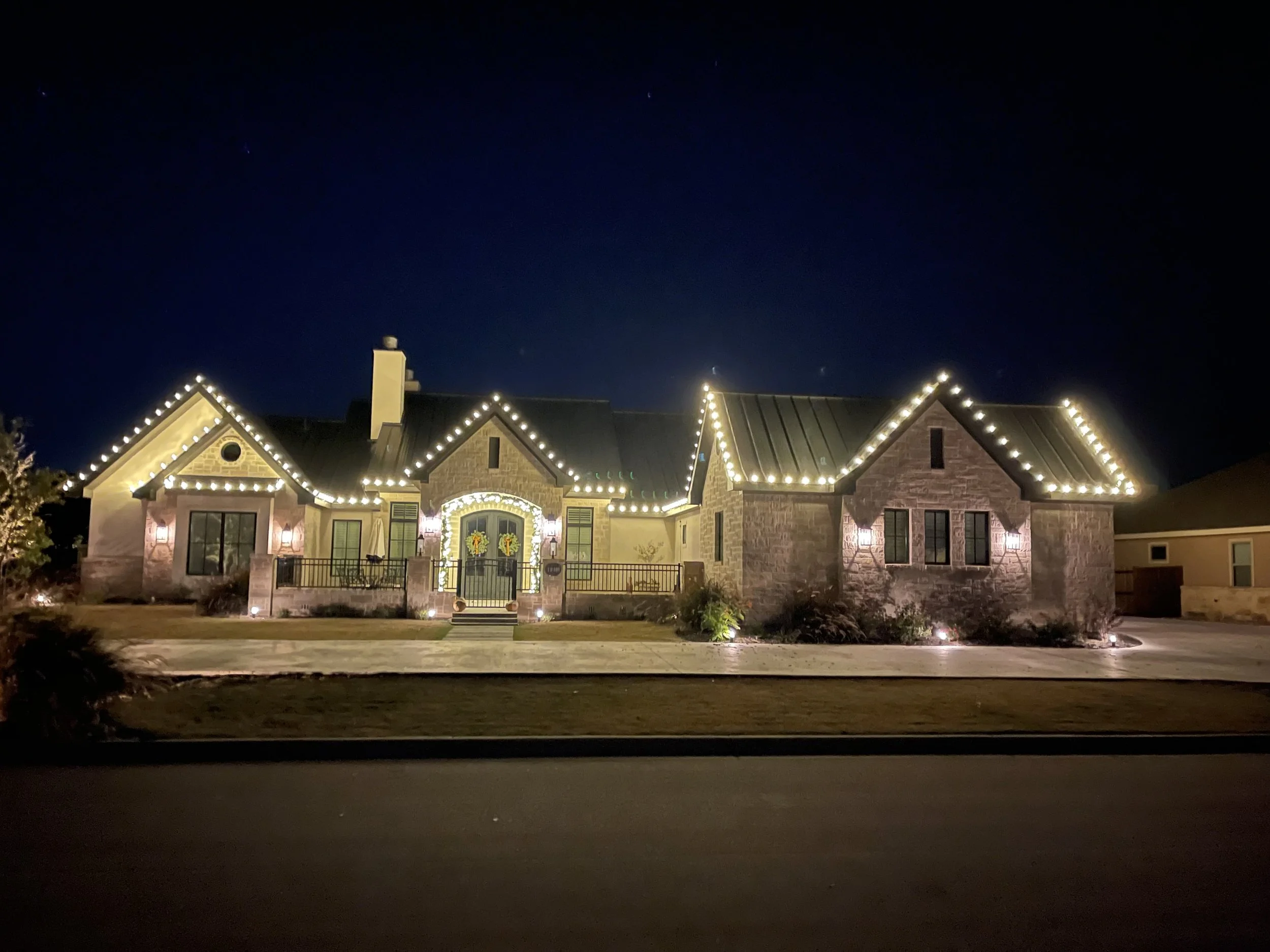 A house decorated with Christmas lights at night, with a dark sky above.