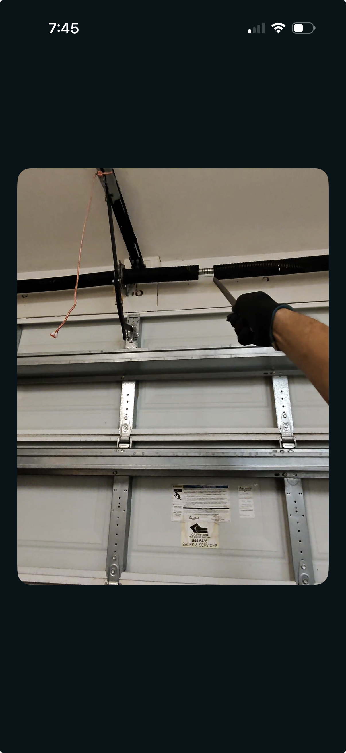 Technician repairing a pair of springs on a garage door during a residential garage door service call.