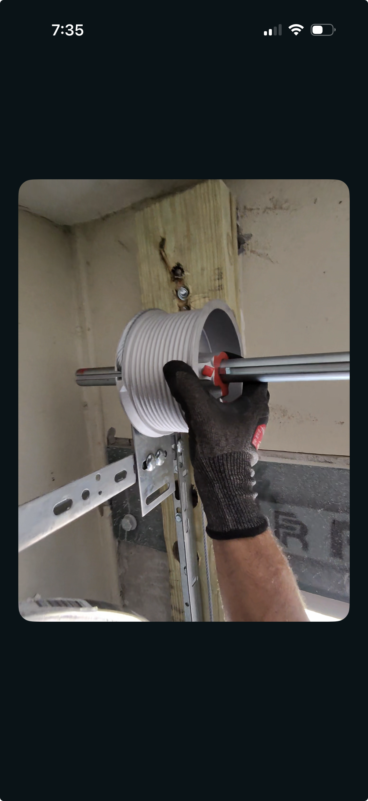A person wearing a glove installs a pulley system on a wooden surface in a construction or DIY project.
