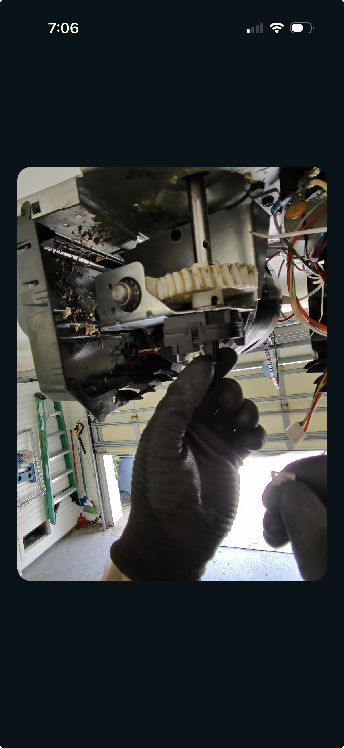 Technician diagnosing a faulty garage door opener circuit board during an opener repair.