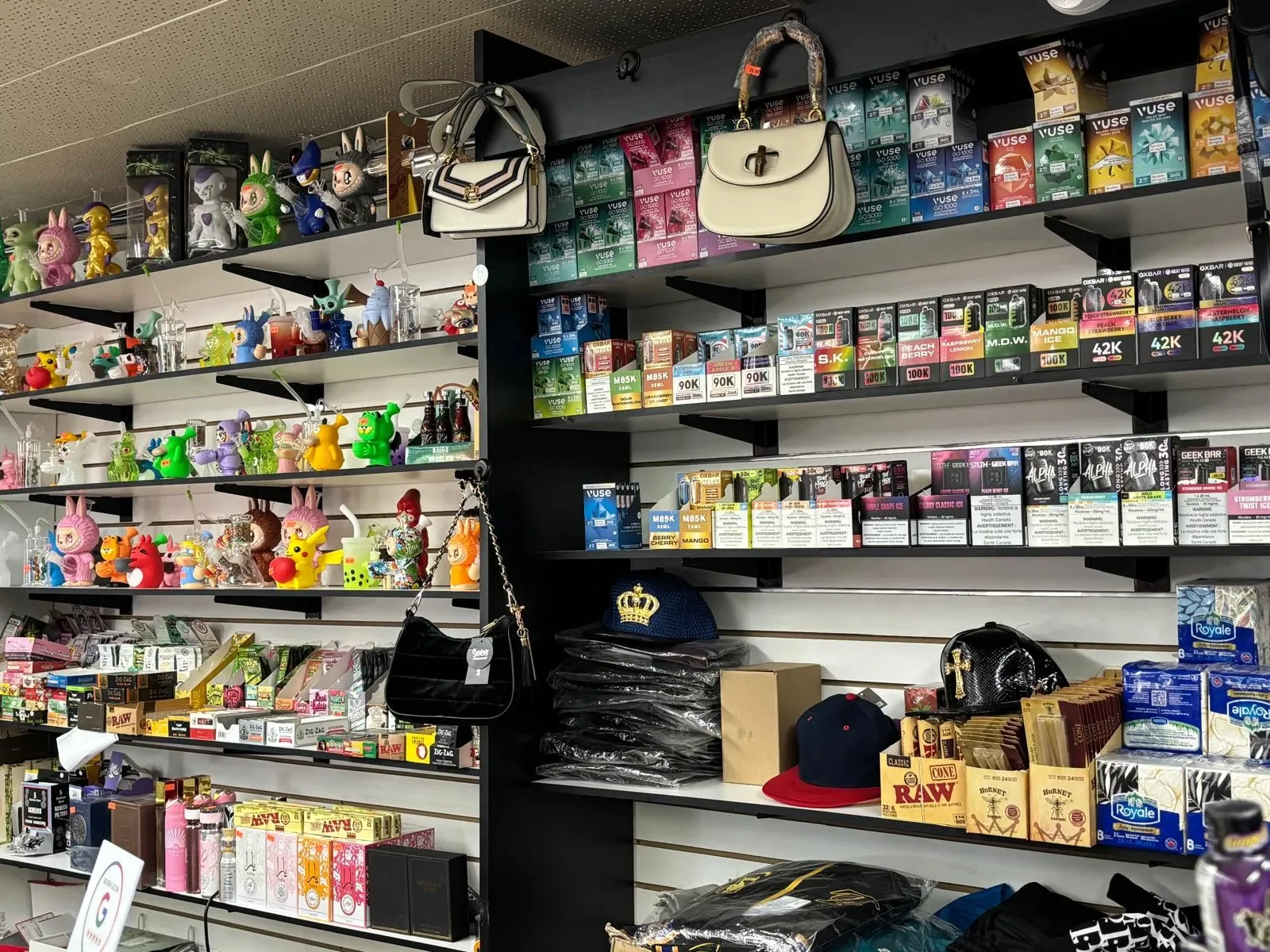 Store shelves filled with various merchandise including toys, bags, boxes of vape products, and clothing accessories.