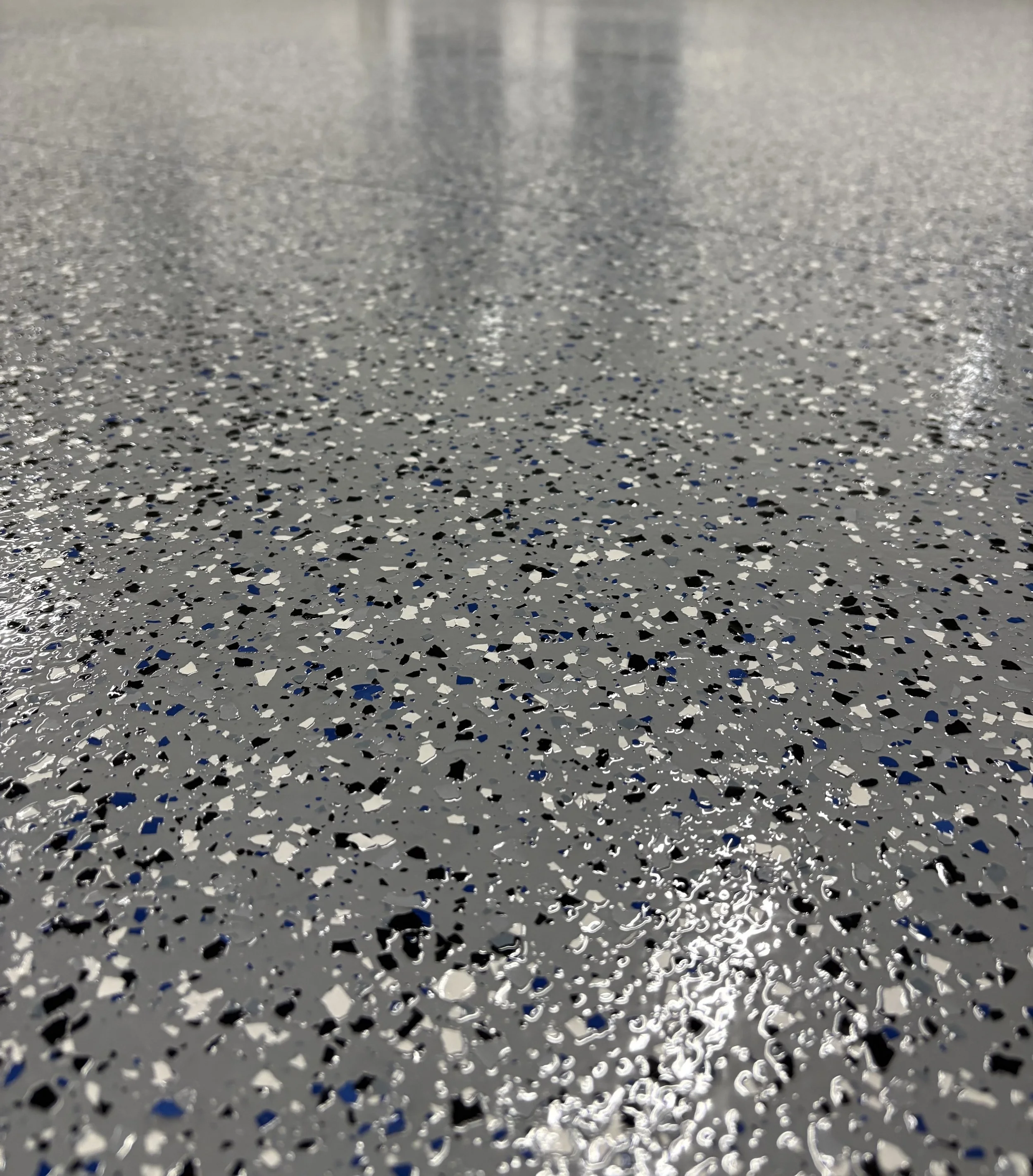 Close-up of a polished terrazzo floor with a speckled pattern of black, white, and gray chips.