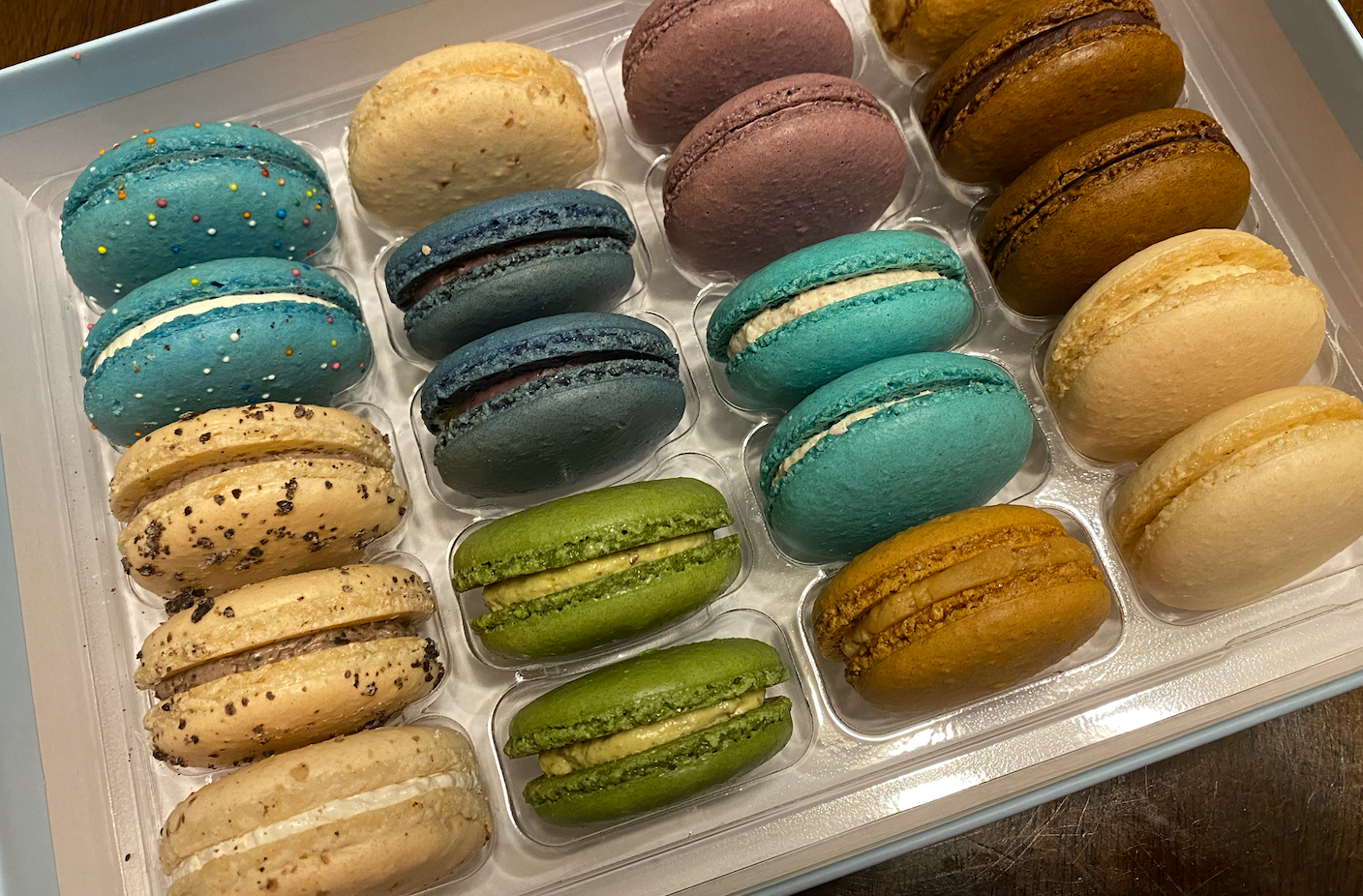Assorted colorful macarons in a plastic container.