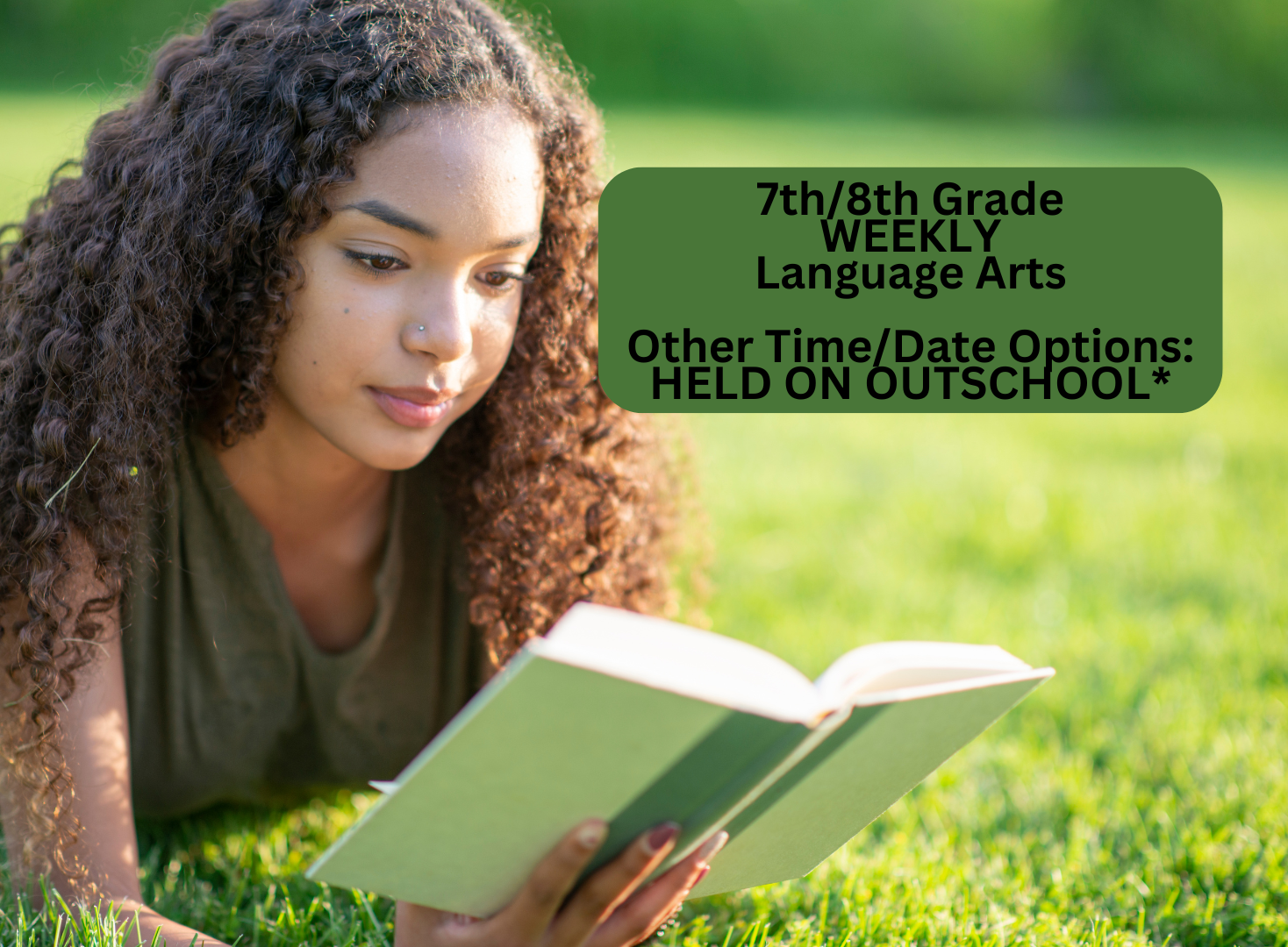 A young woman with curly hair, reading a book outdoors on a sunny day with green grass in the background.
