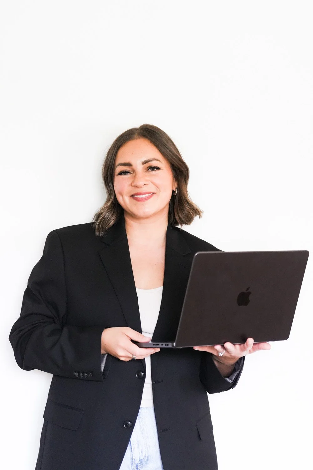 Bree Graham smiling in a black blazer while holding a laptop.