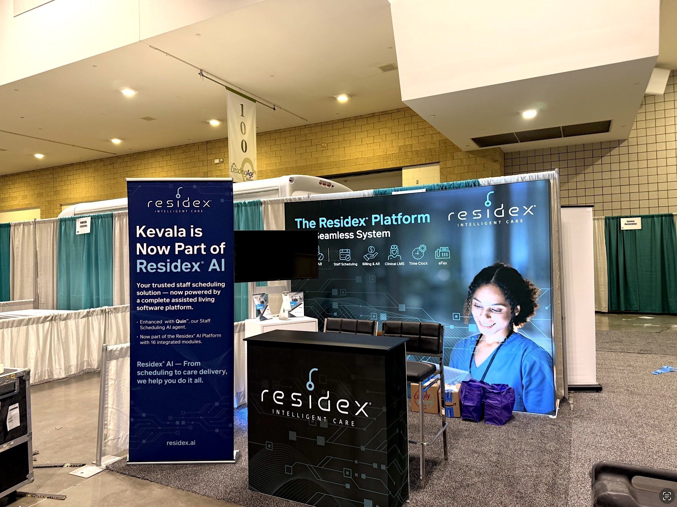 Exhibition booth for Residex AI, featuring banners with information about the company's healthcare system platform, a woman smiling, and various promotional materials.