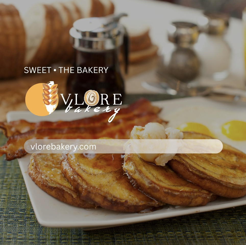 A breakfast plate with fried potatoes topped with butter, sunny side up eggs, and crispy bacon. In the background, there are slices of bread, a jar of syrup, and salt and pepper shakers on a table.