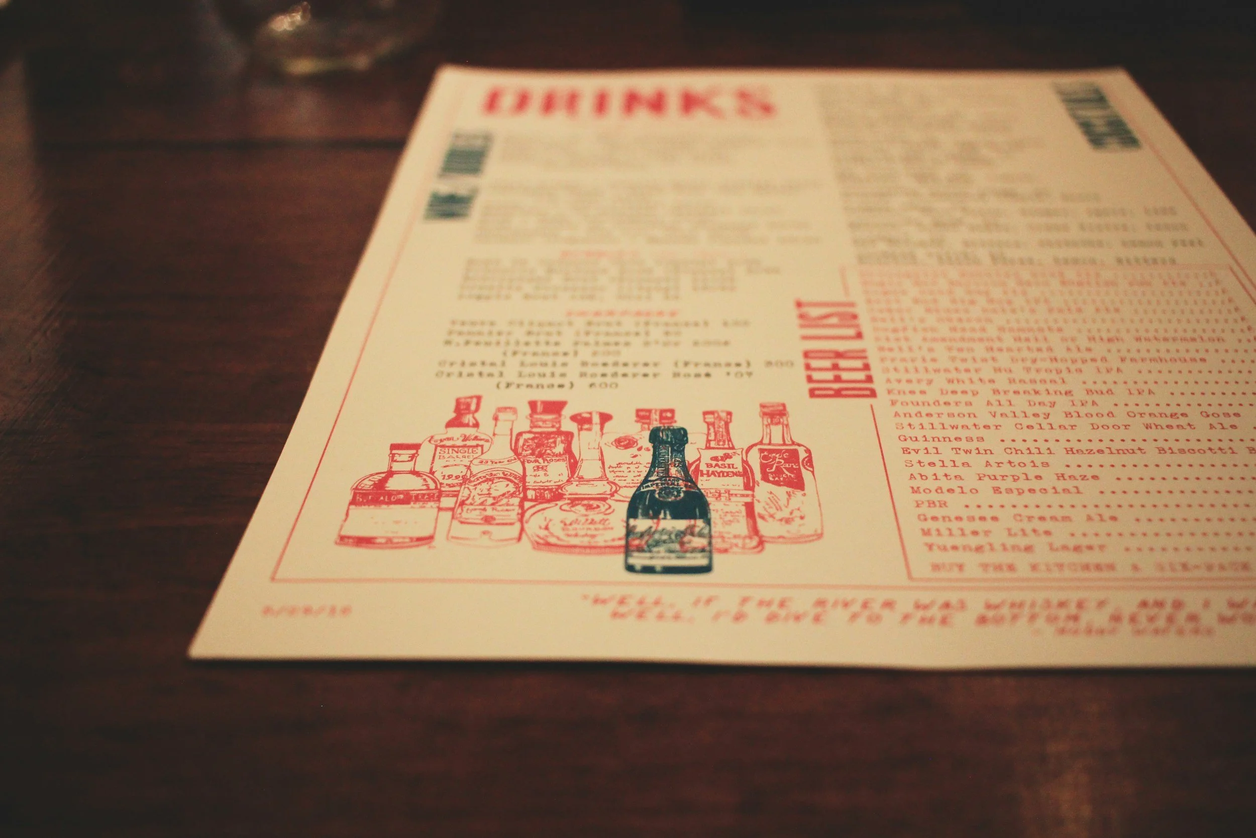 A blurry menu on a wooden table at a restaurant or bar.