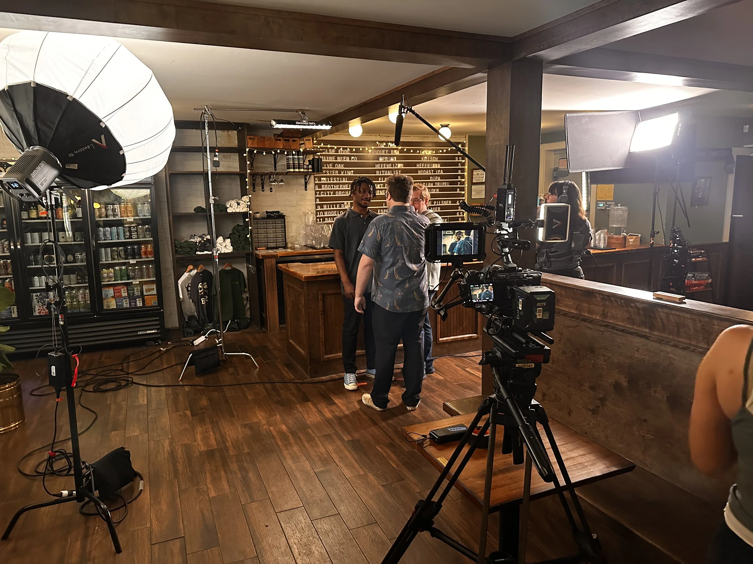 Film crew setting up lighting and camera equipment in a restaurant or café for filming.