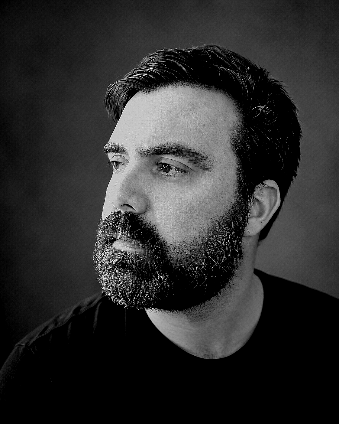 Black and white portrait of a man with a beard and mustache, looking off to the side.