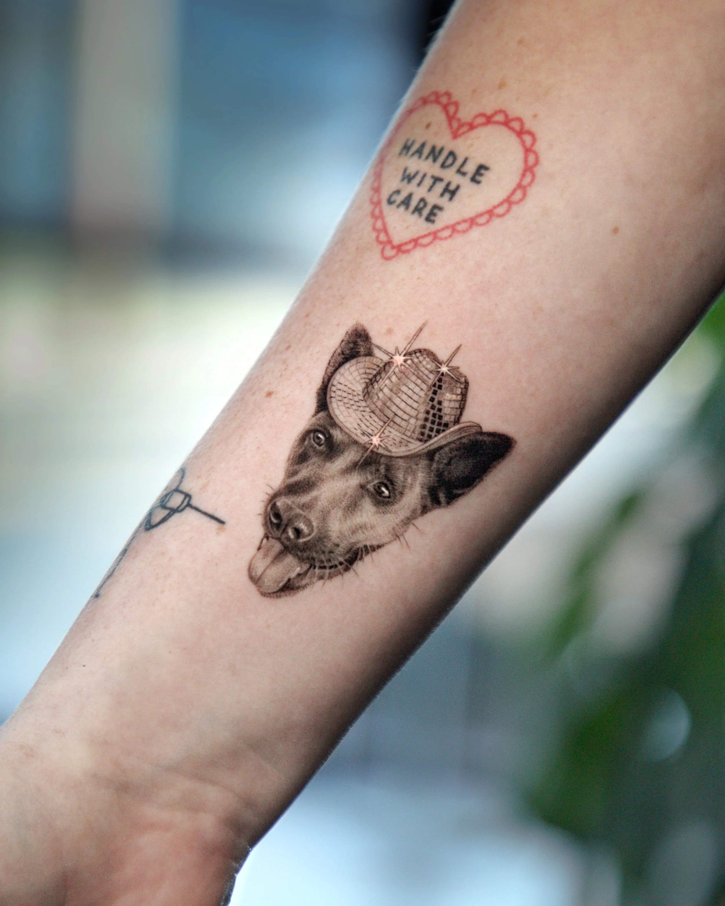 A hyper realistic tattoo done by Ihor (flowerhead.ink) on person's forearm. Featuring a micro realistic dog portrait with a disco hat on. 